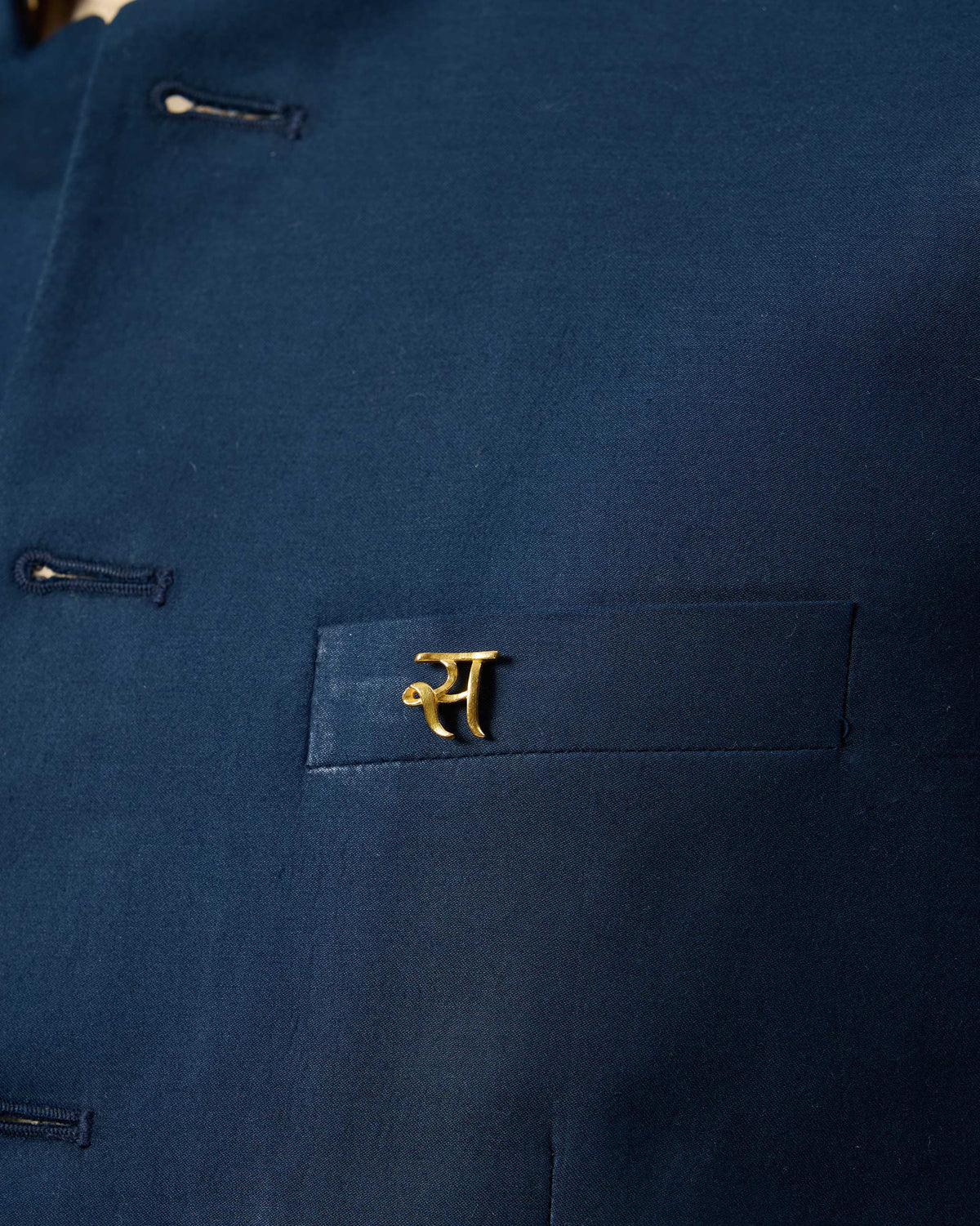 Gold Alphabet S Pin pinned to a navy jacket pocket.