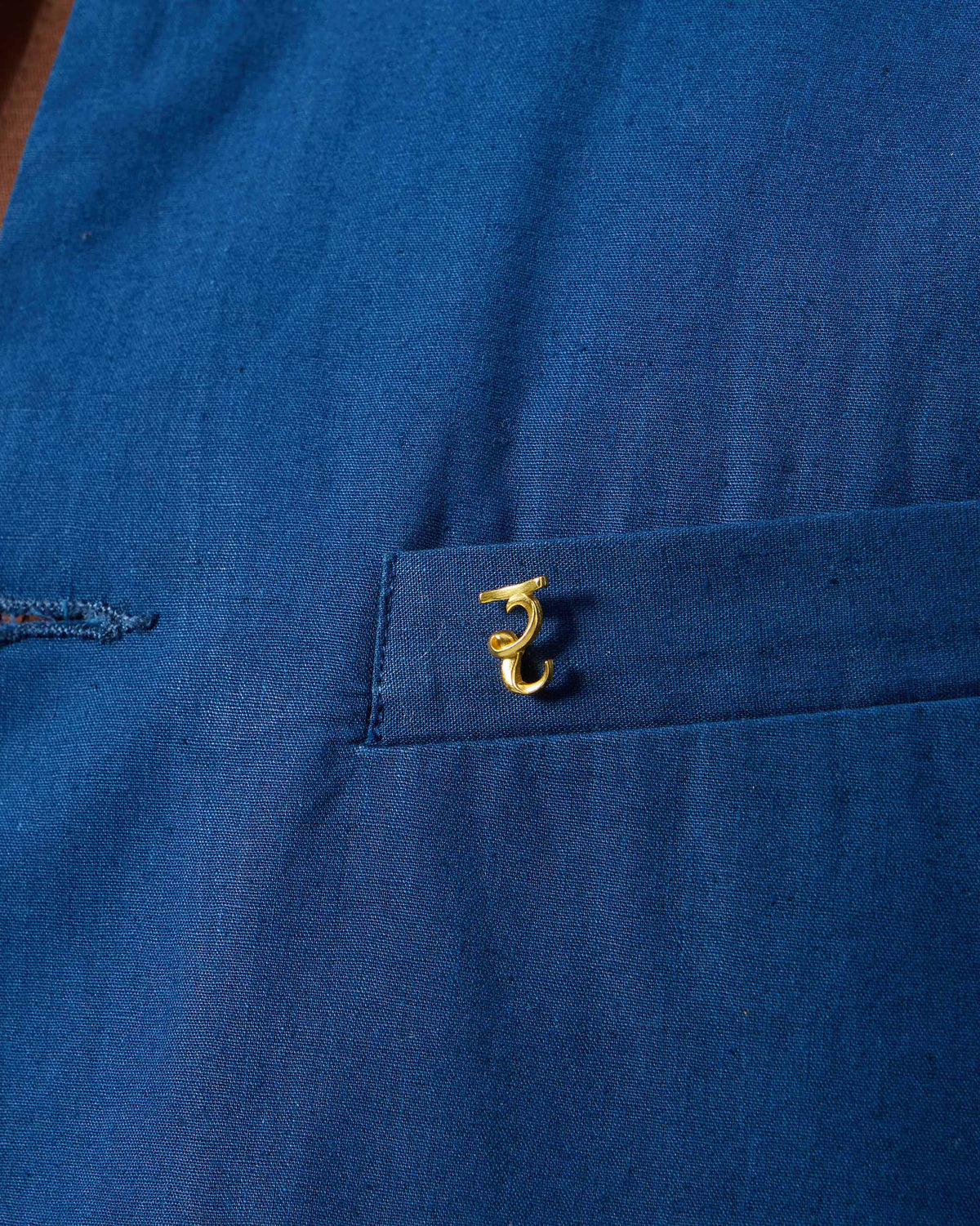 Close-up of Alphabet R Pin in gold on a navy pocket.