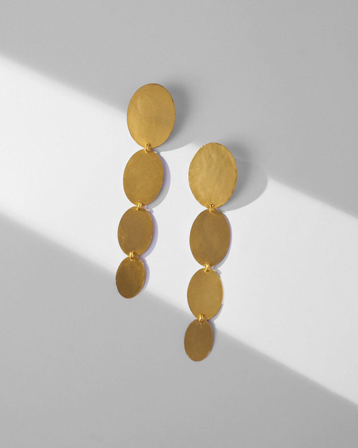 Pair of gold Drift Danglers laid flat, each with four oval discs.