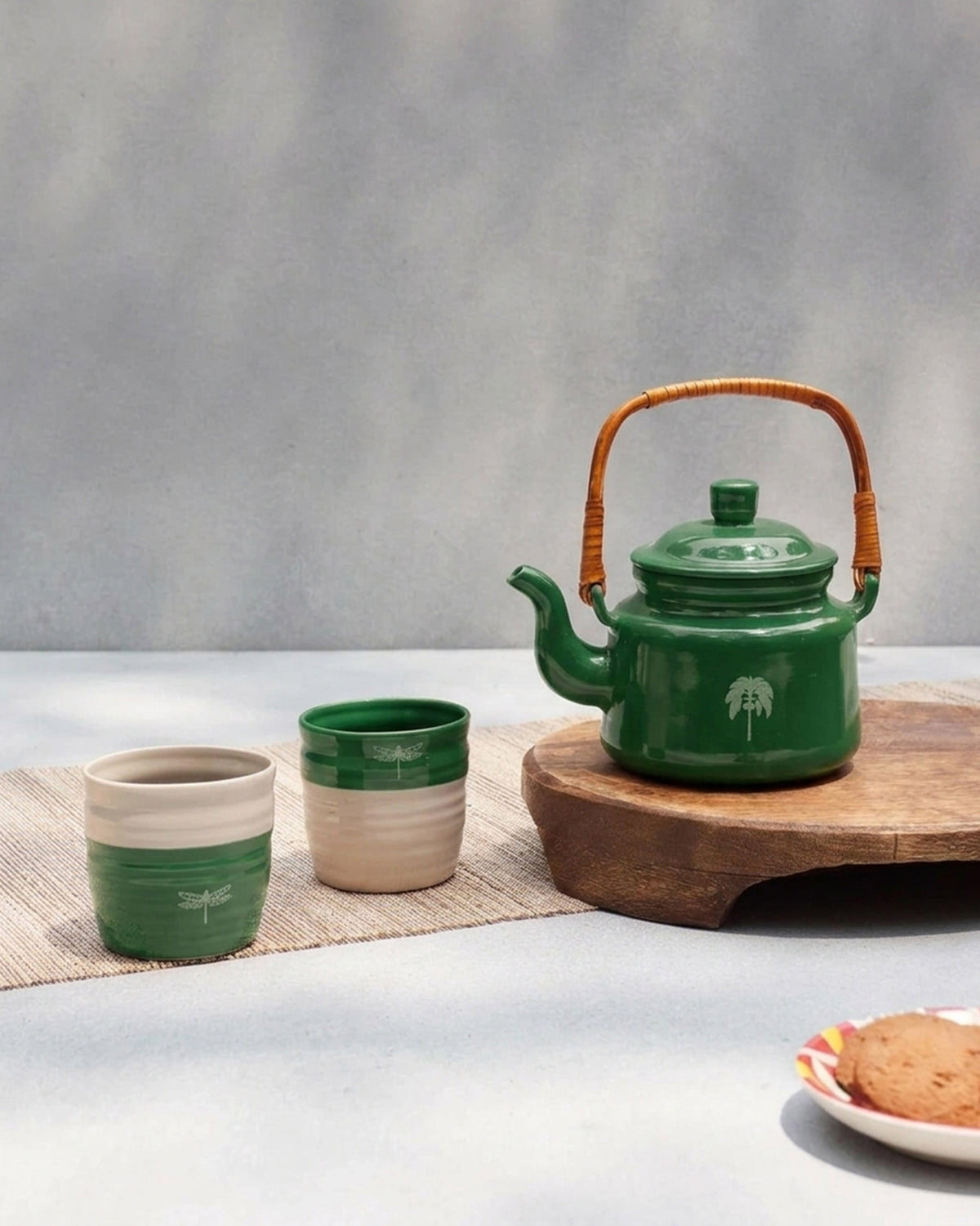 Virid Tea Set with a green teapot with rattan handle and two green and cream cups.