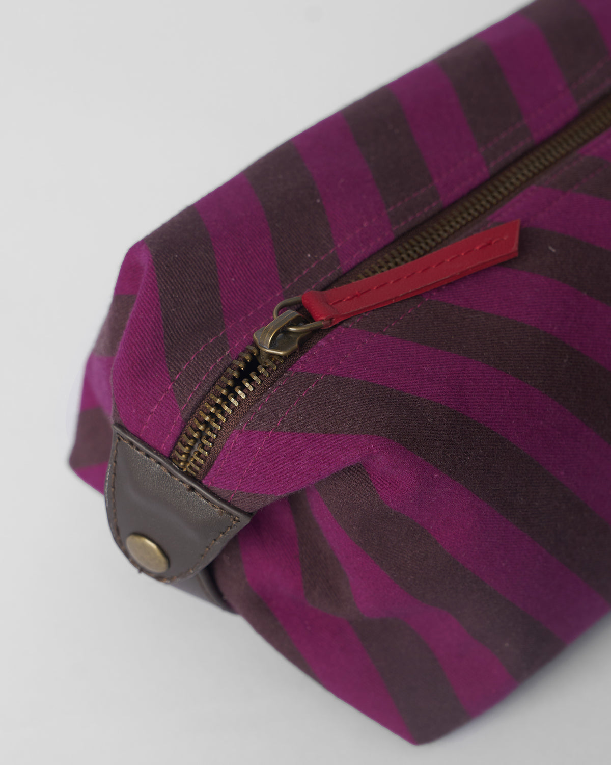 Close-up of the red leather zipper pull on a brown and mulberry Cupid Pouch.