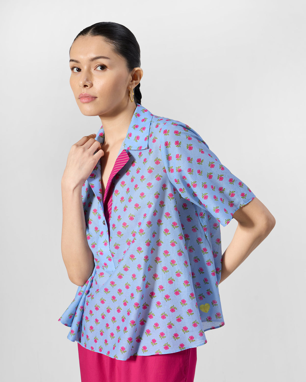 Person wearing an ice blue Rann shirt with short sleeves and a pink rose print.
