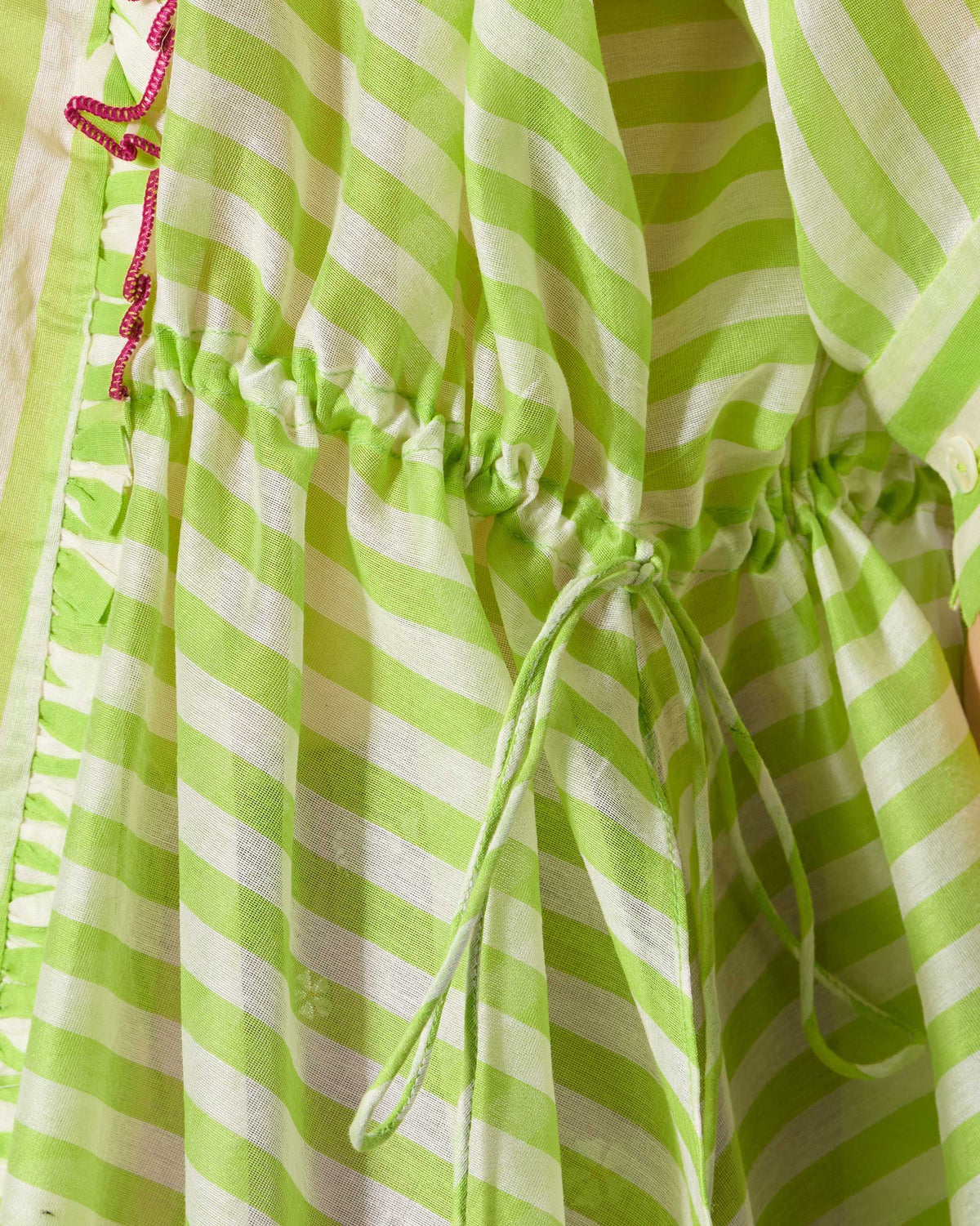 Close-up of a lime and ivory Manoor top drawstring waist with pink embroidered trim.