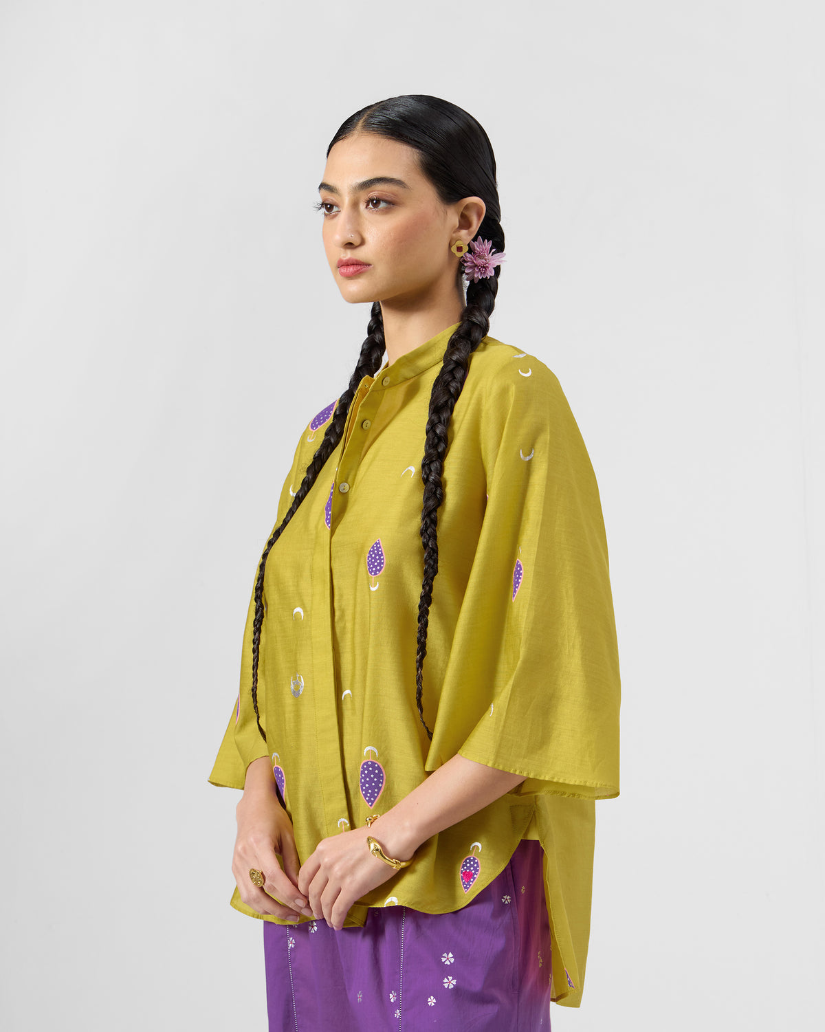 Angled view of a chartreuse Chilika high-low shirt with purple motifs.