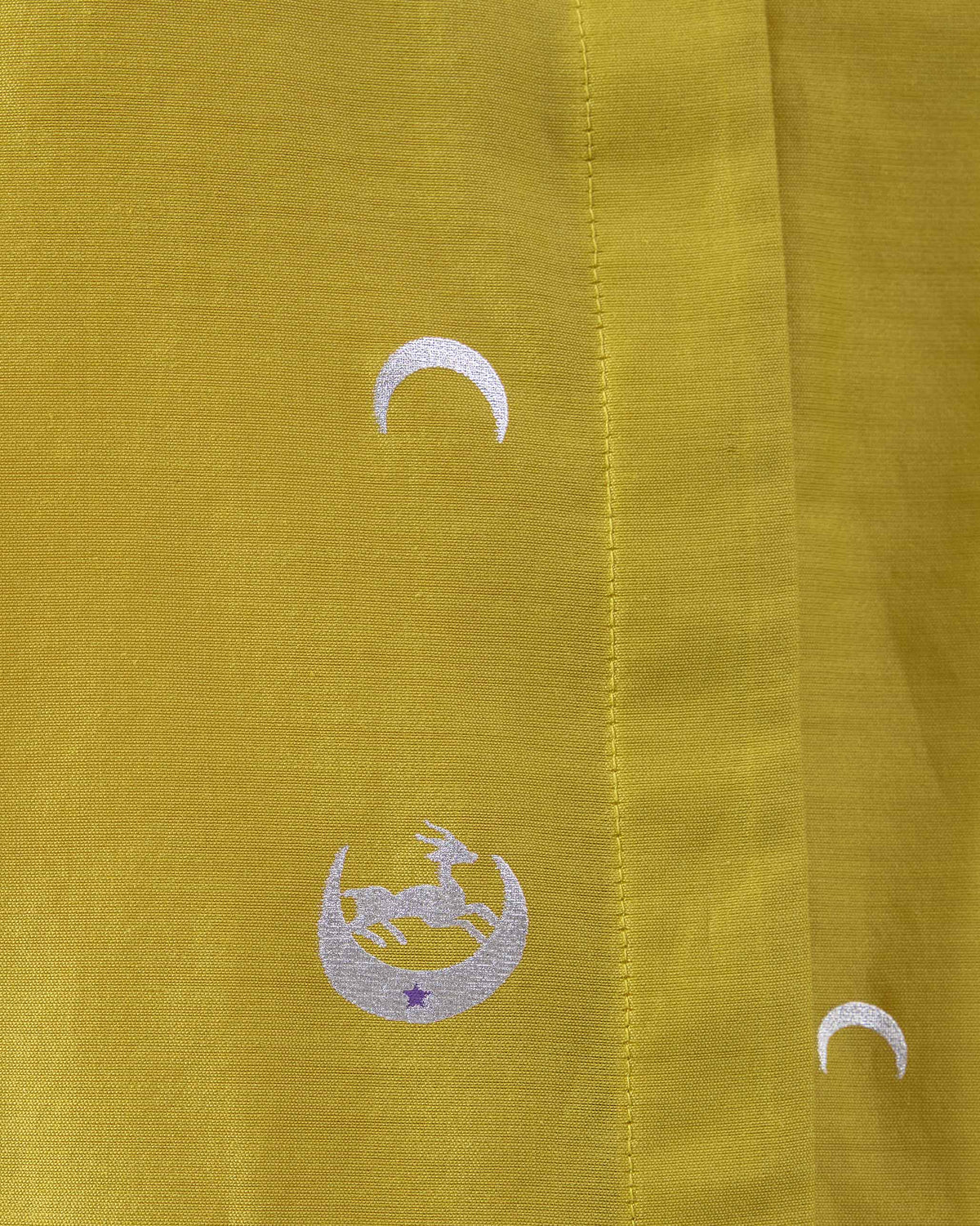 Close-up of a silver deer embroidery on a chartreuse Chilika shirt.