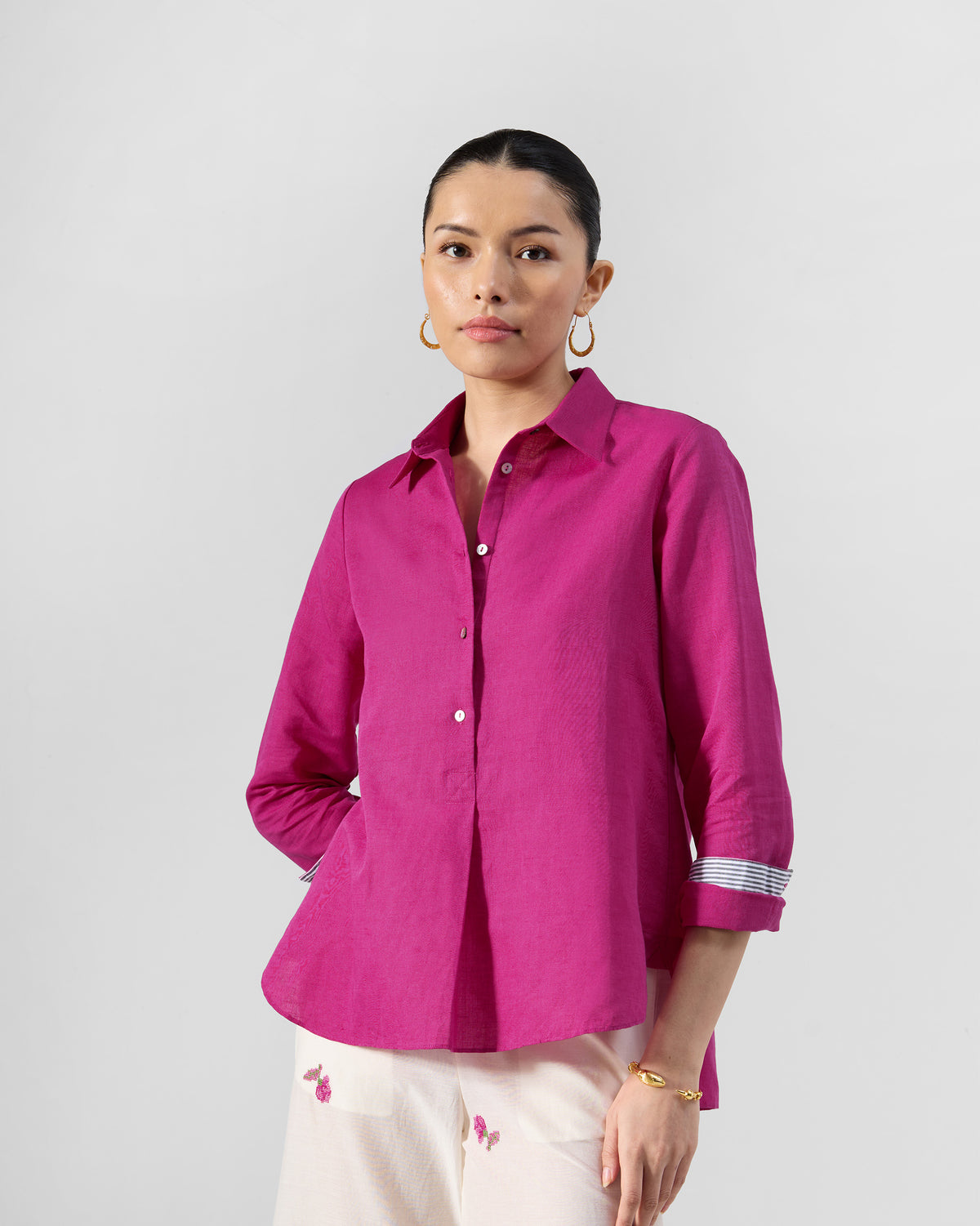 Person wearing a berry pink Mati shirt with striped cuff lining.
