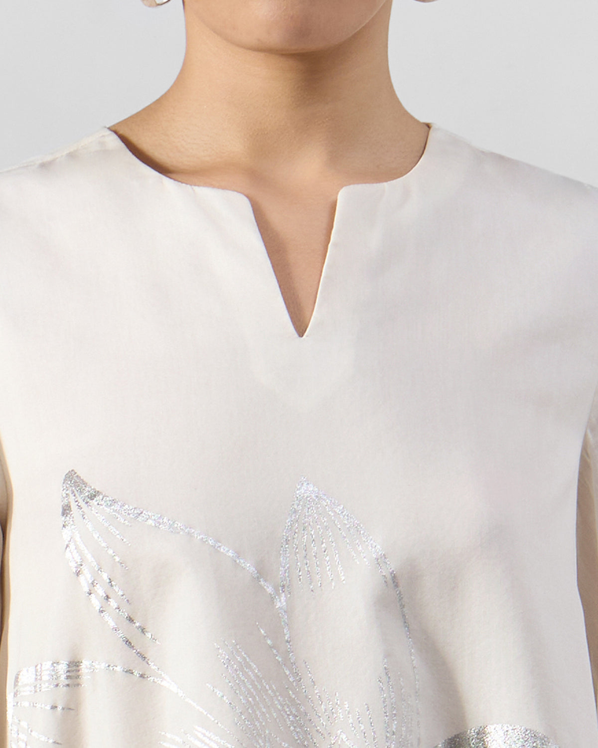 Close-up of the V-neck and silver foil print on an ivory Vaya kurta.
