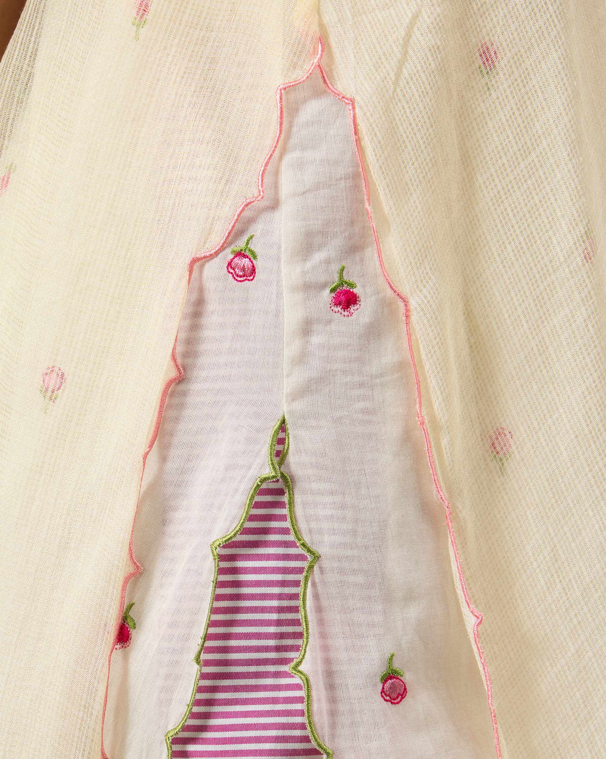 Close-up of scalloped layers with pink rosebud embroidery on an ivory Hera Halter Kurta.