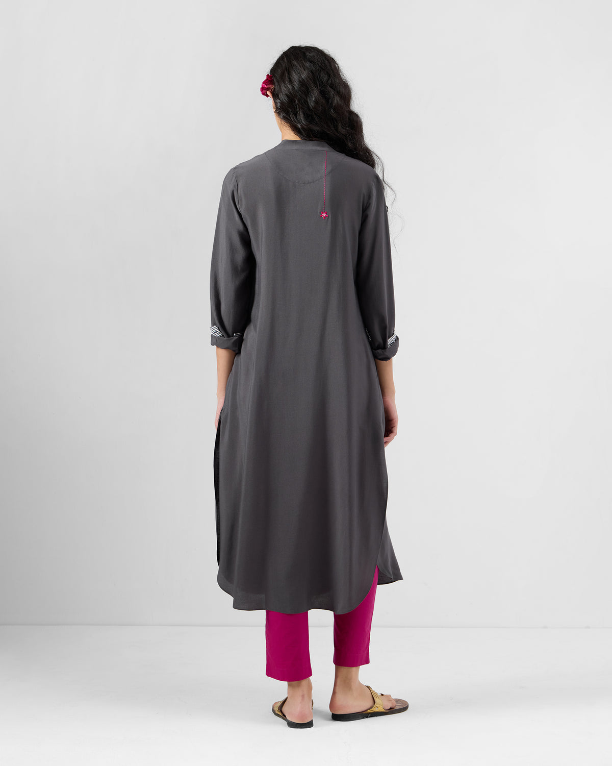 Back of a charcoal silk-blend long kurta with a pink embroidered flower below the collar.