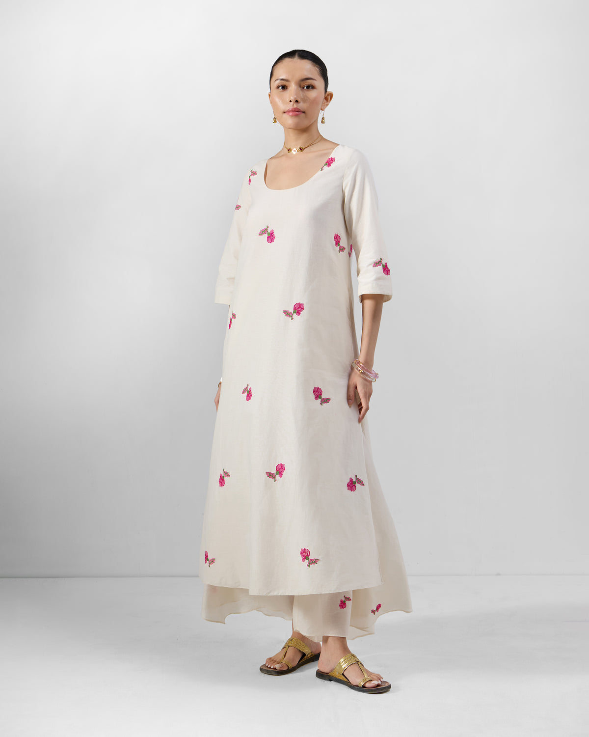 Person wearing an ivory Amrai Kurta with pink floral embroidery.