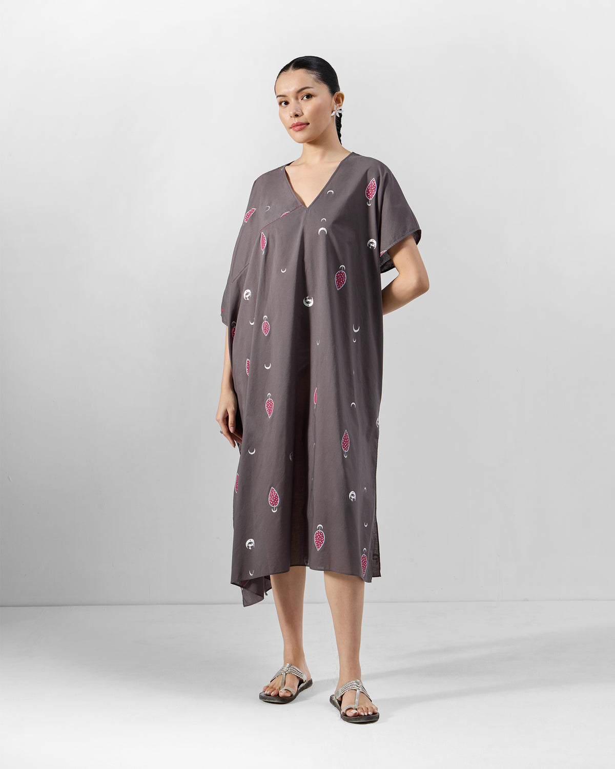 Person wearing a charcoal Faye Kaftan with a V-neck and pink scattered motifs.