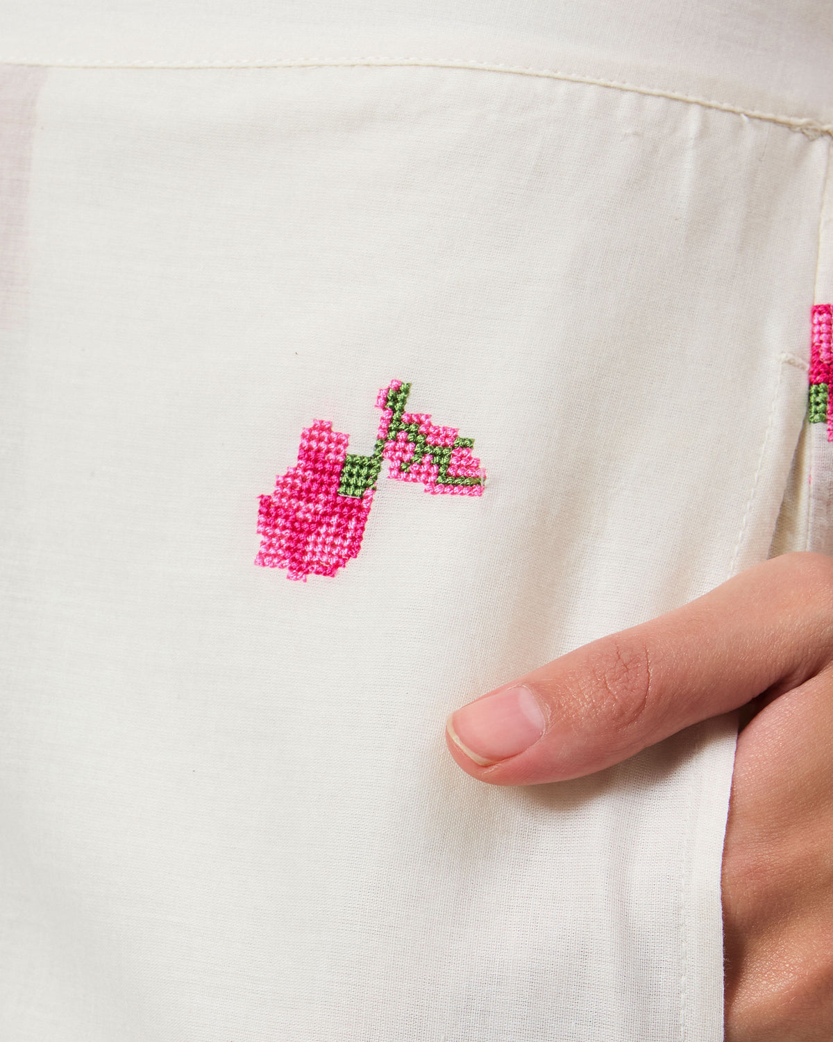 Close-up of pink floral embroidery on white Raahi pants.