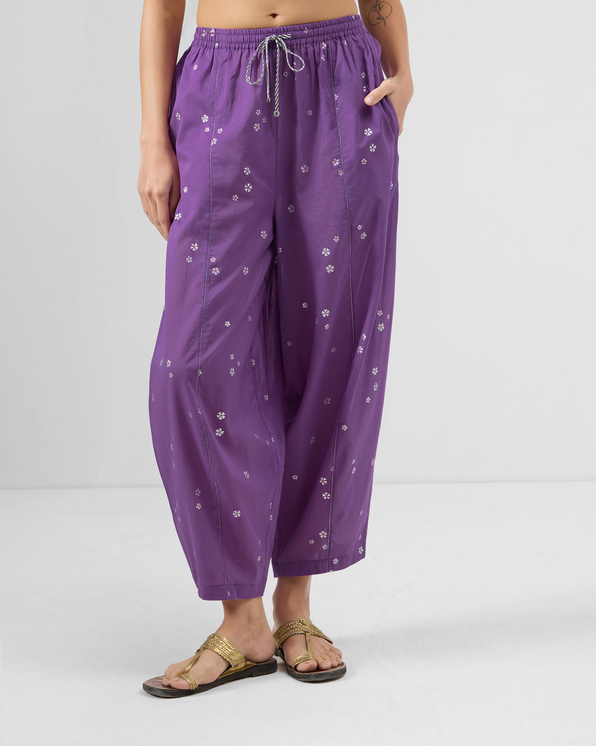 Purple cotton Bora pants with a white floral print and striped drawstring waist.