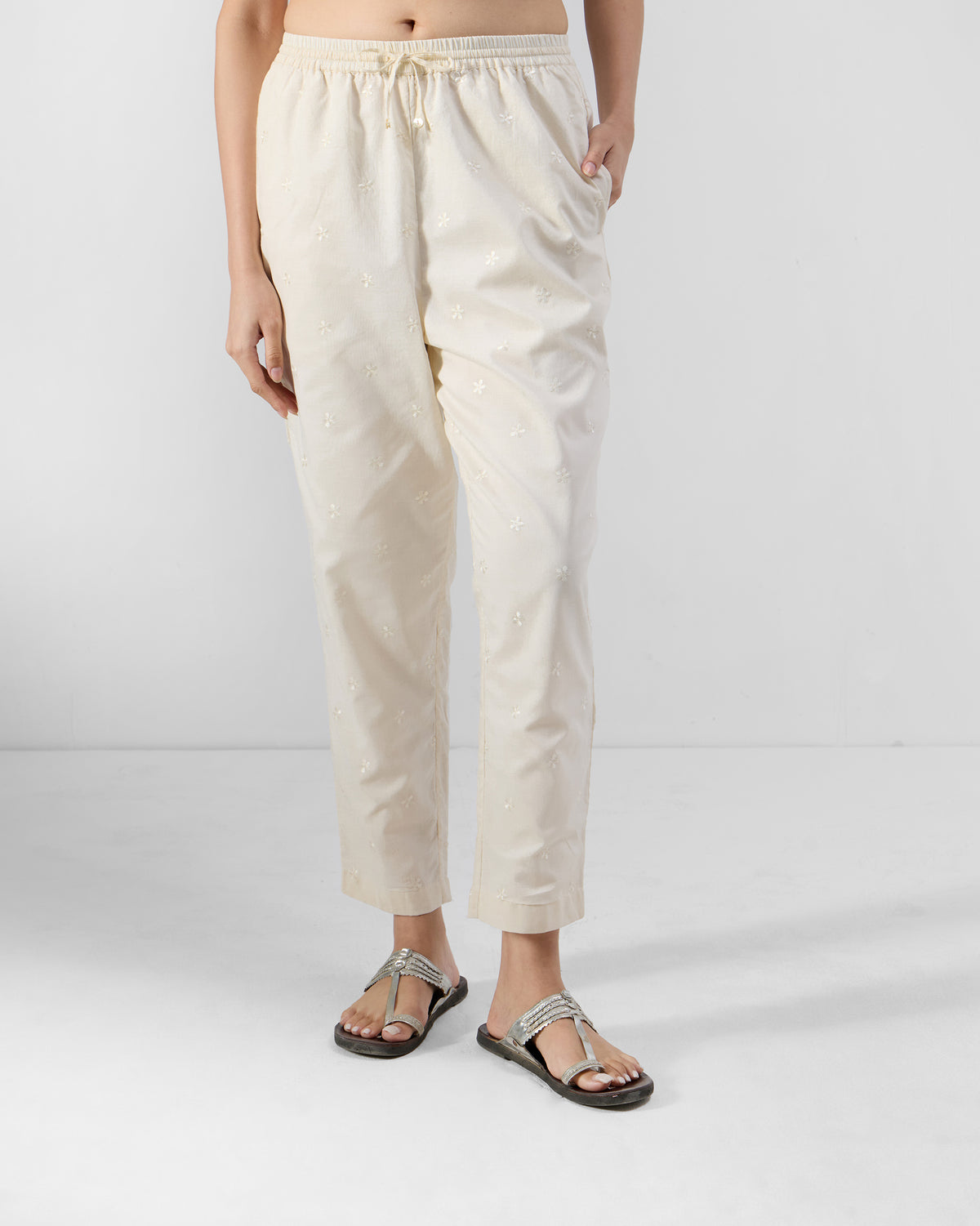 Person wearing ivory embroidered Kintara Pants with a drawstring waist.