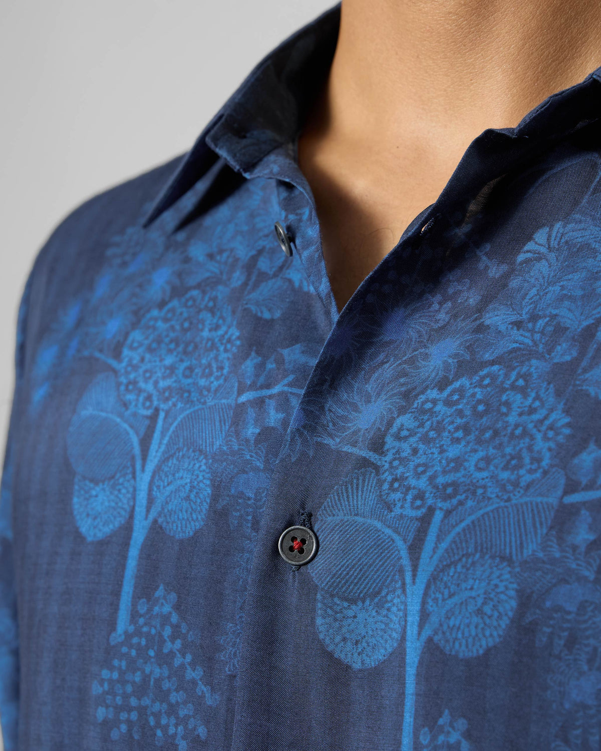 Close-up of a navy Hakuna shirt collar with a blue floral print.