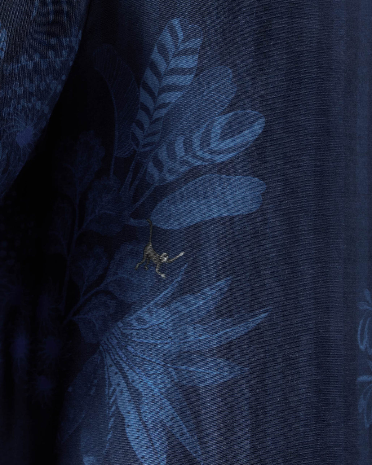 Close-up of a navy Hakuna shirt print showing a hanging monkey.