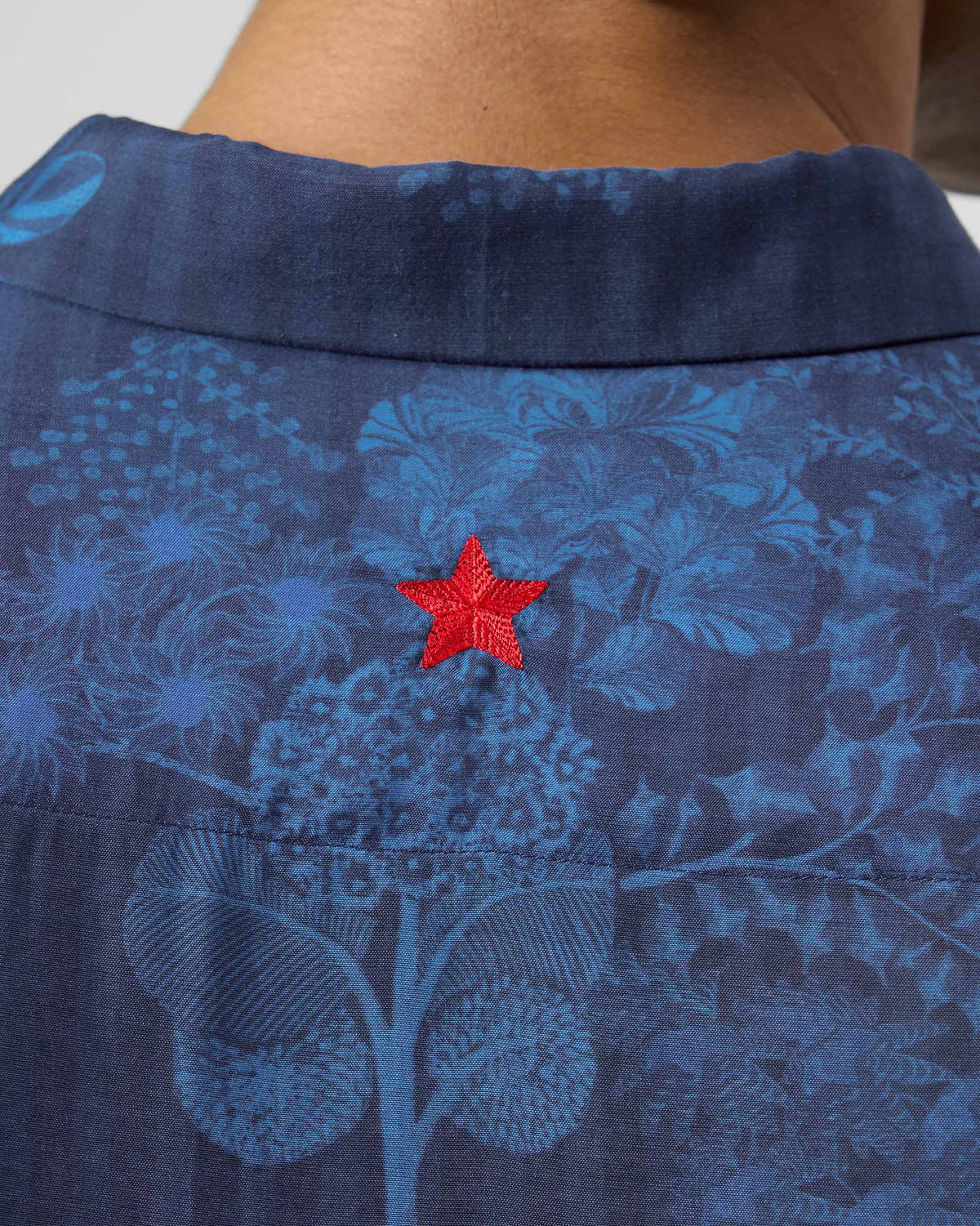 Close-up of a red star on the back of a navy Hakuna shirt.