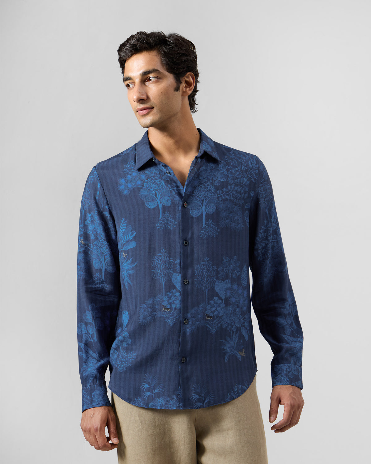 Person wearing a navy Hakuna shirt with a tonal forest print.