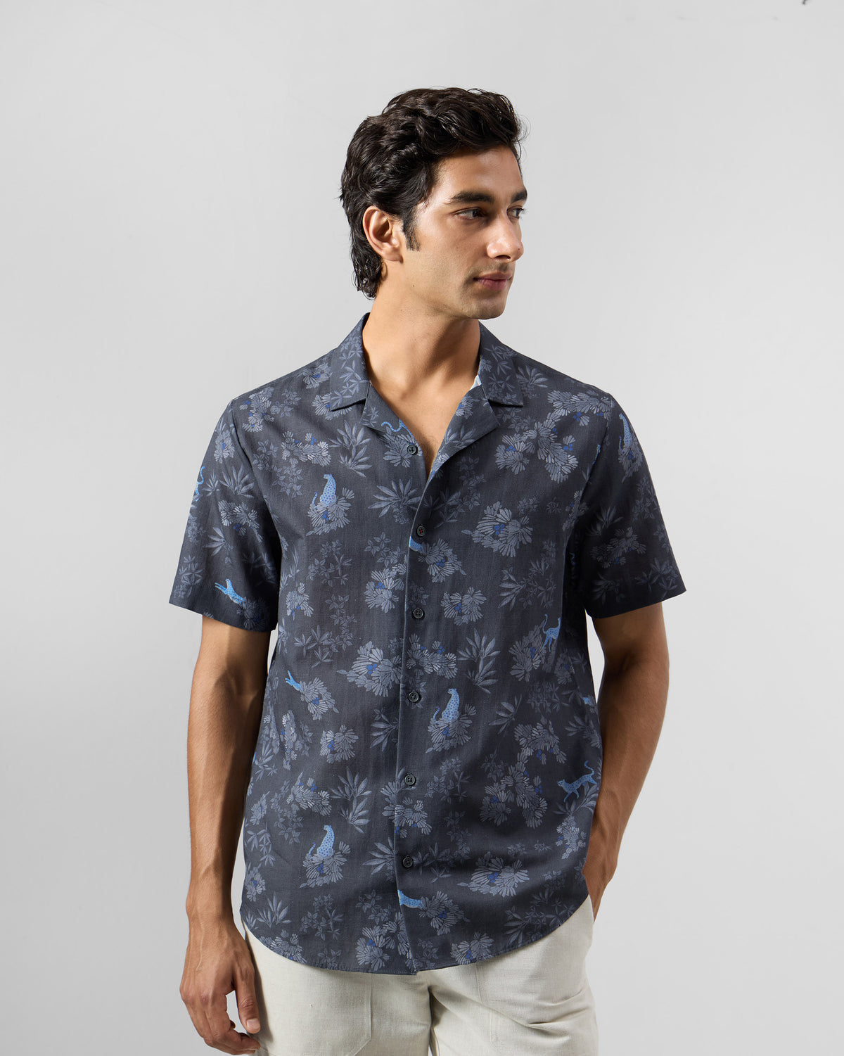 Person wearing a charcoal Mistari Shirt with a blue leopard and foliage print.