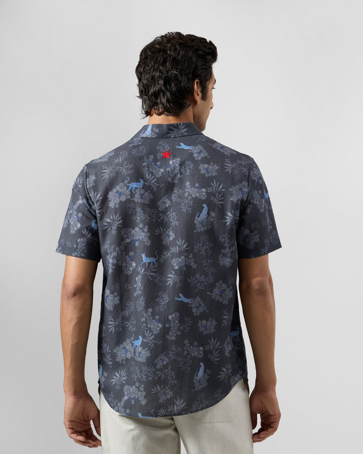 Back of a charcoal Mistari Shirt with a blue leopard print and a red embroidered star.