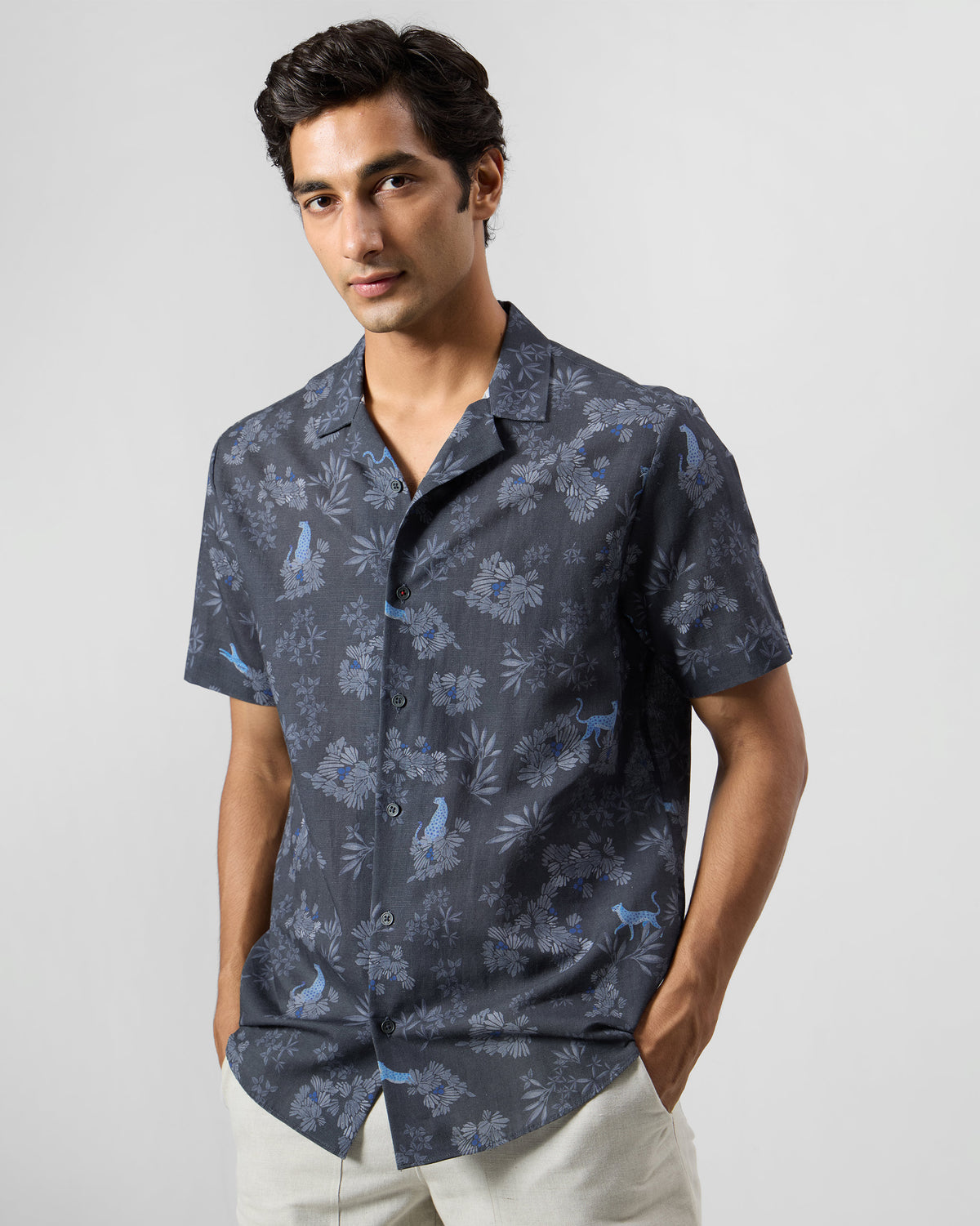 Person wearing a charcoal Mistari Shirt with a blue leopard and foliage print.