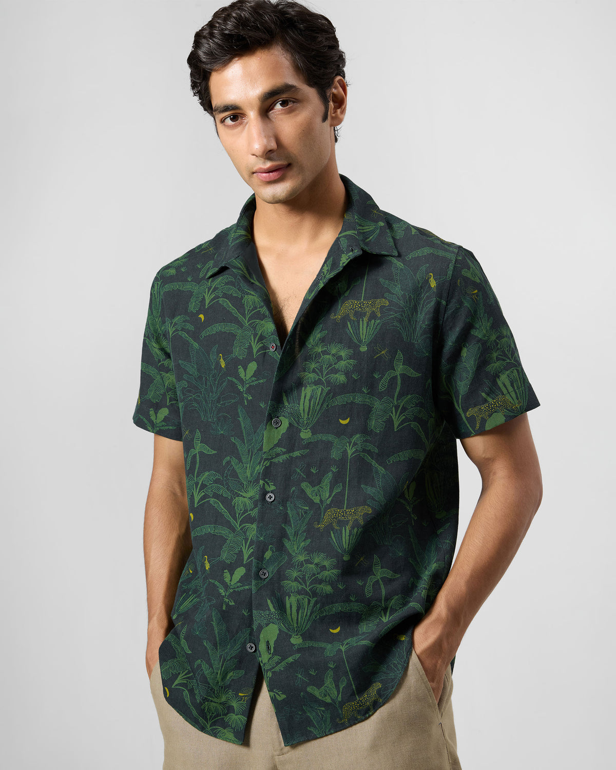 Person wearing a green Half Sleeve Shirt with a jungle print of leopards and leaves.