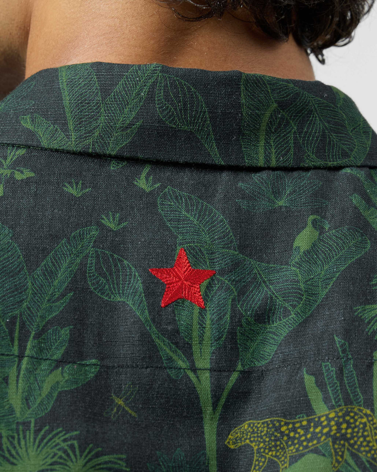 Close-up of the red star on the back of a green jungle-print Half Sleeve Shirt.