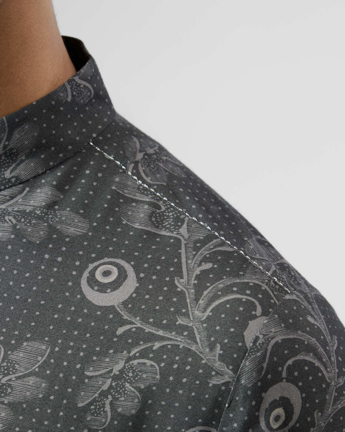 Close-up of white shoulder stitching on a charcoal printed Rey Kurta.