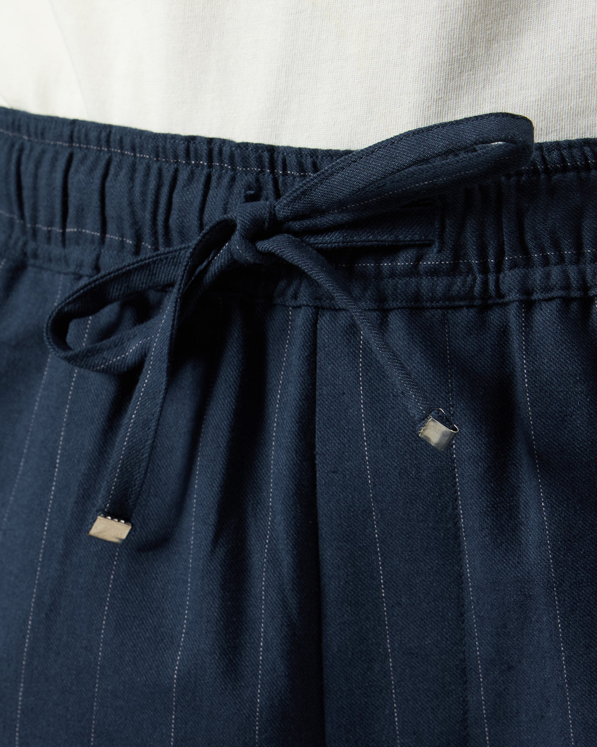 Close-up of a navy Vera trouser drawstring waistband with metal tips.