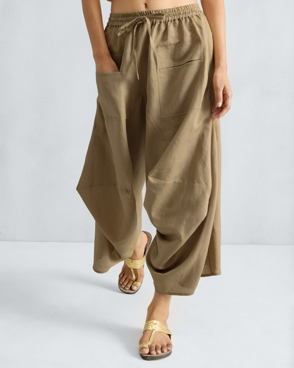 Person wearing taupe Yoka Trousers with a drawstring waist and patch pockets.