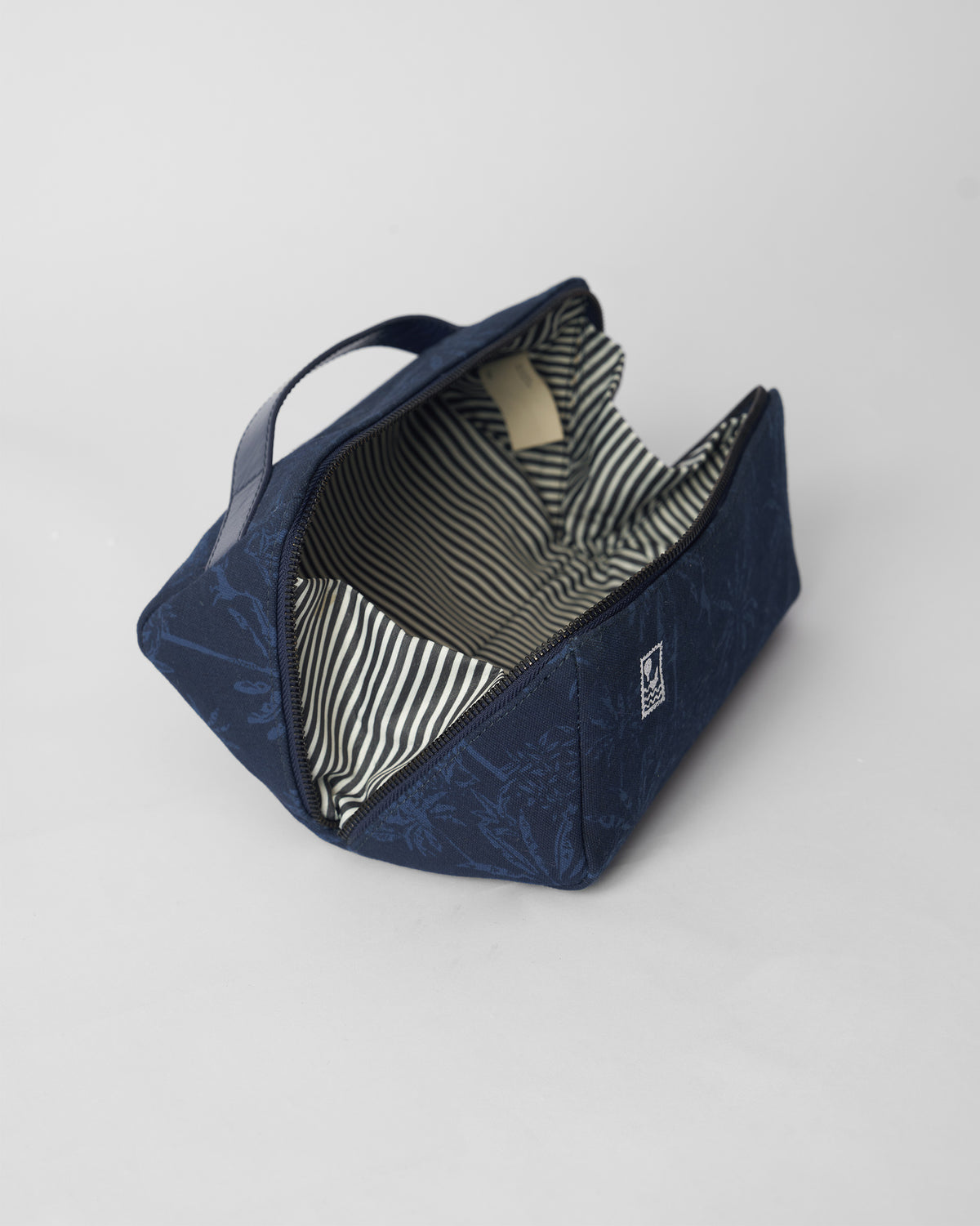Open navy Palm dopp kit showing a striped lining.