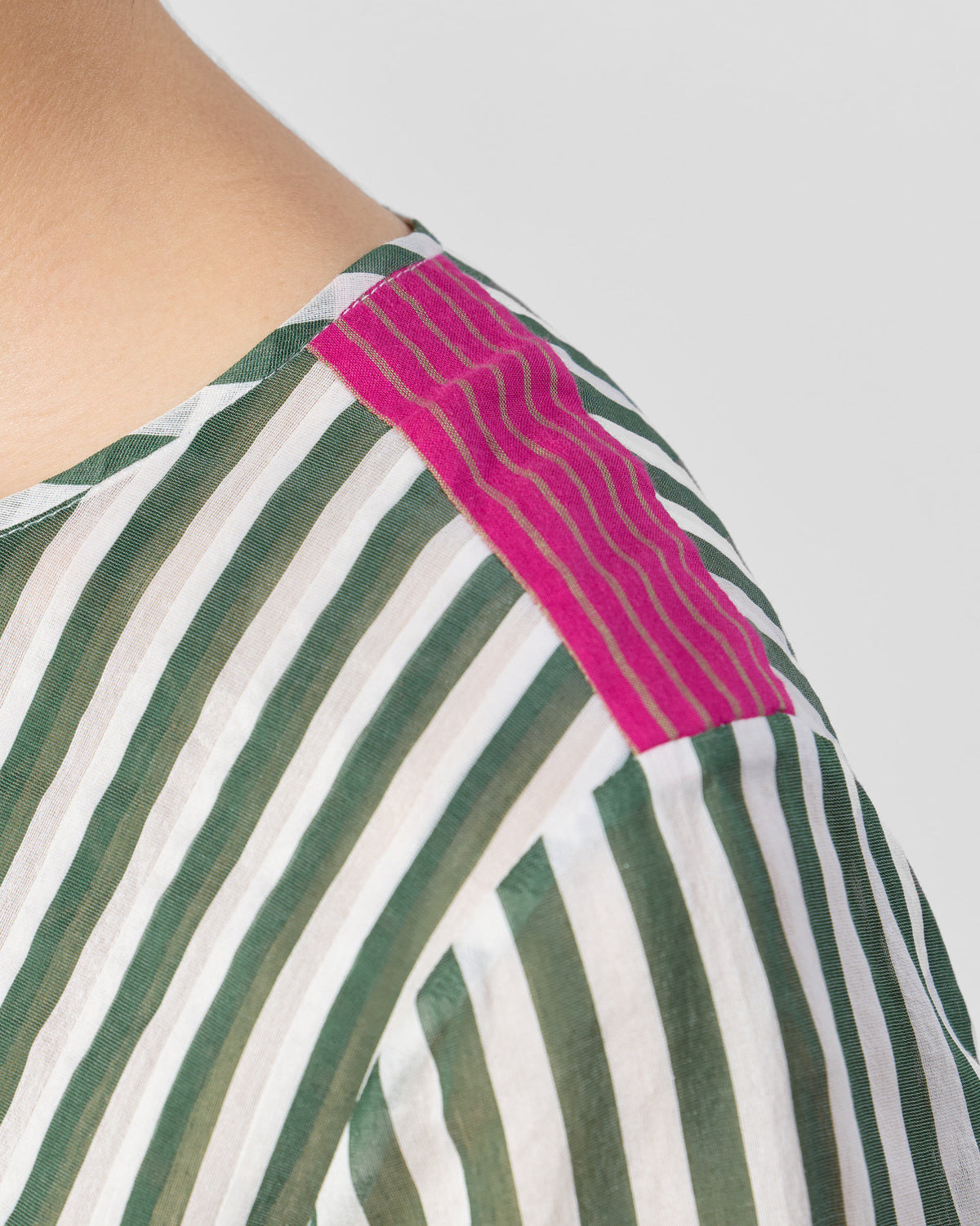 Close-up of a magenta shoulder patch on an emerald-and-ivory striped Konark kurta.