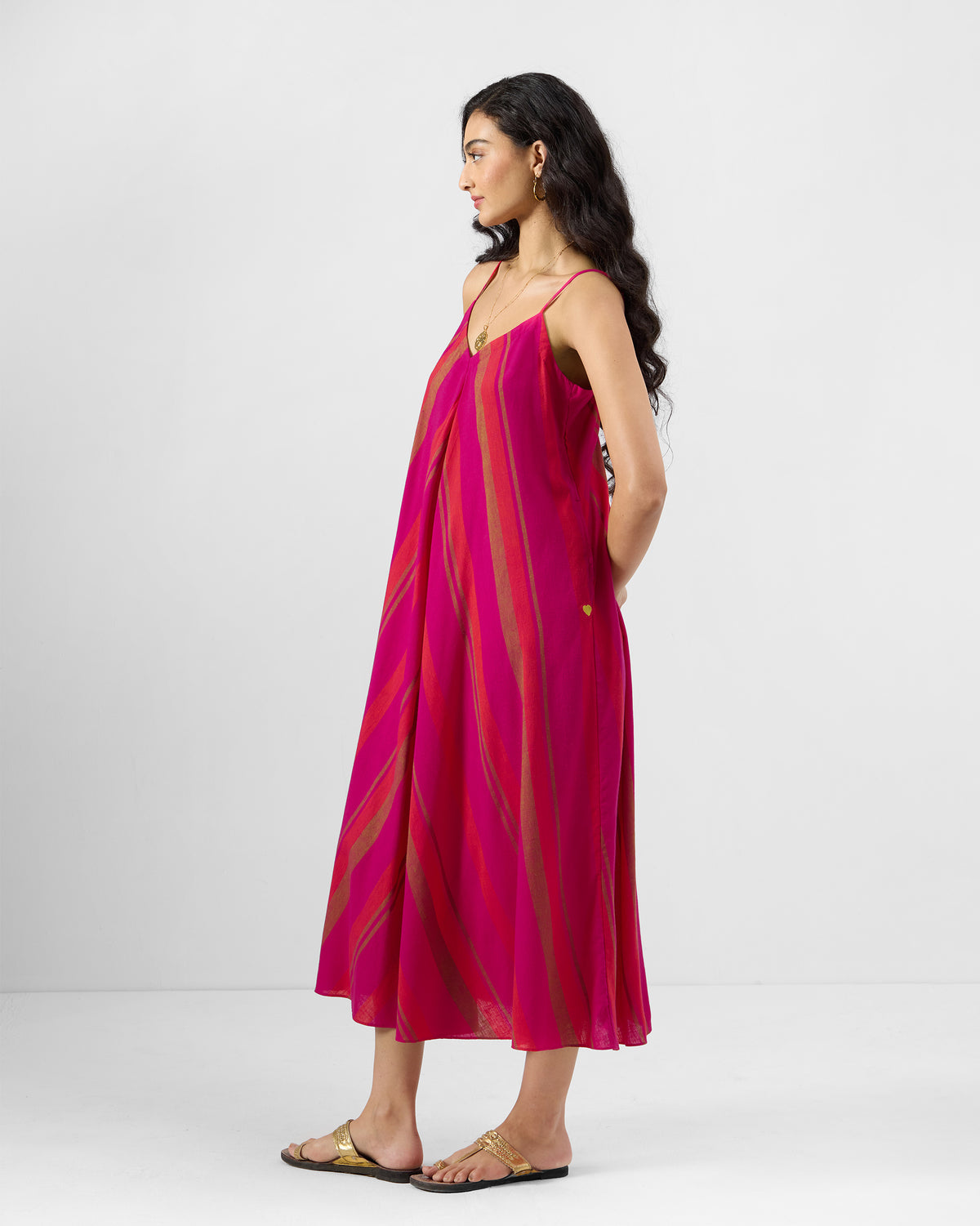 Pink and orange Narali strappy dress with diagonal stripes worn at an angle.
