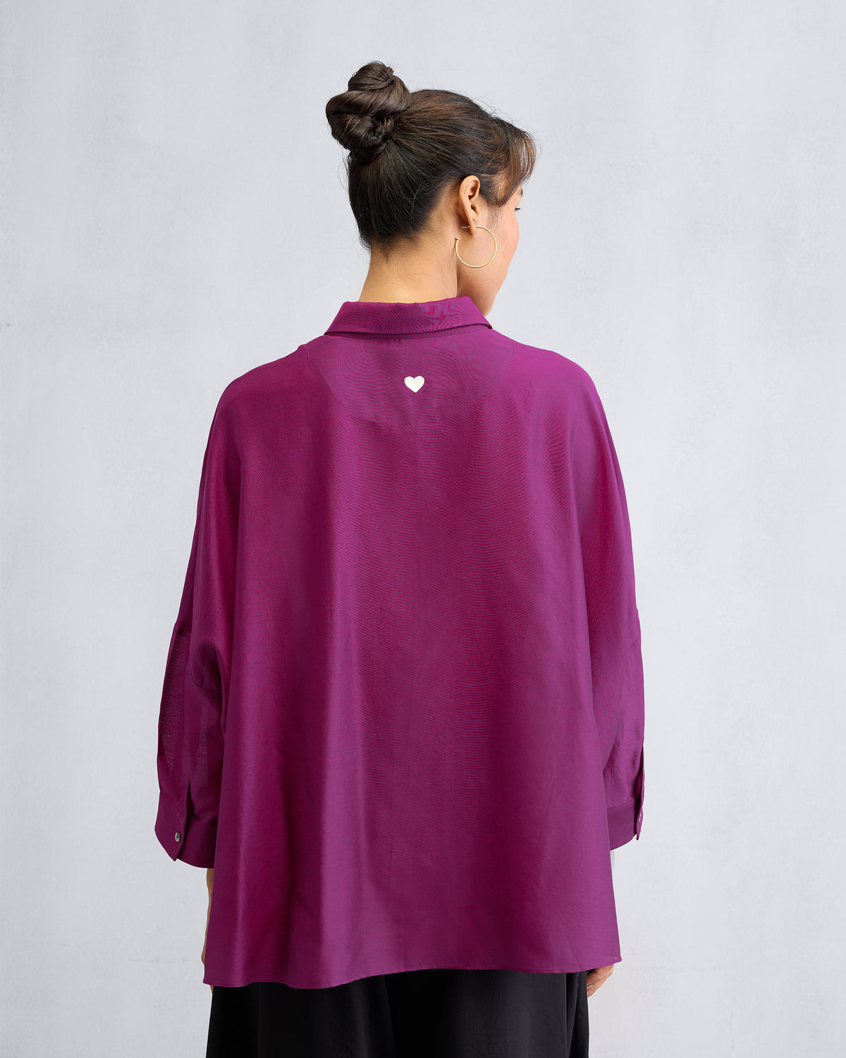 Back of a mulberry boxy shirt with a white embroidered heart below the collar.