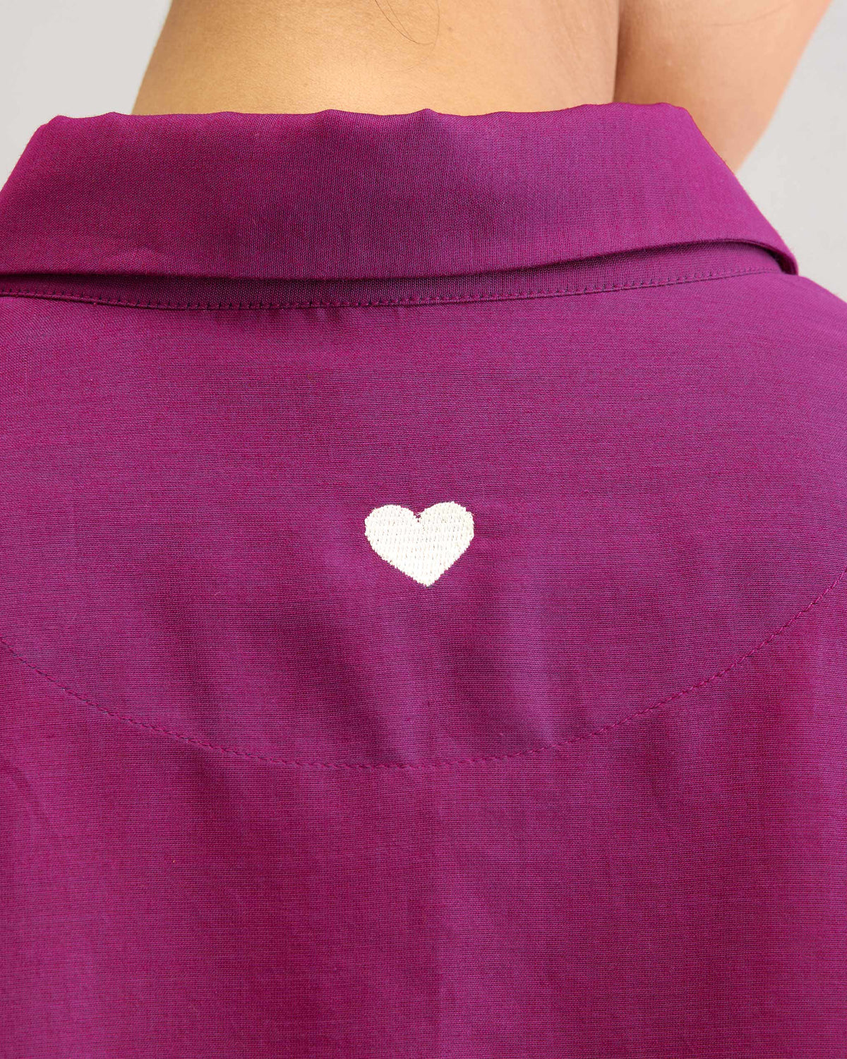 Close-up of a white embroidered heart on the back of a mulberry boxy shirt.