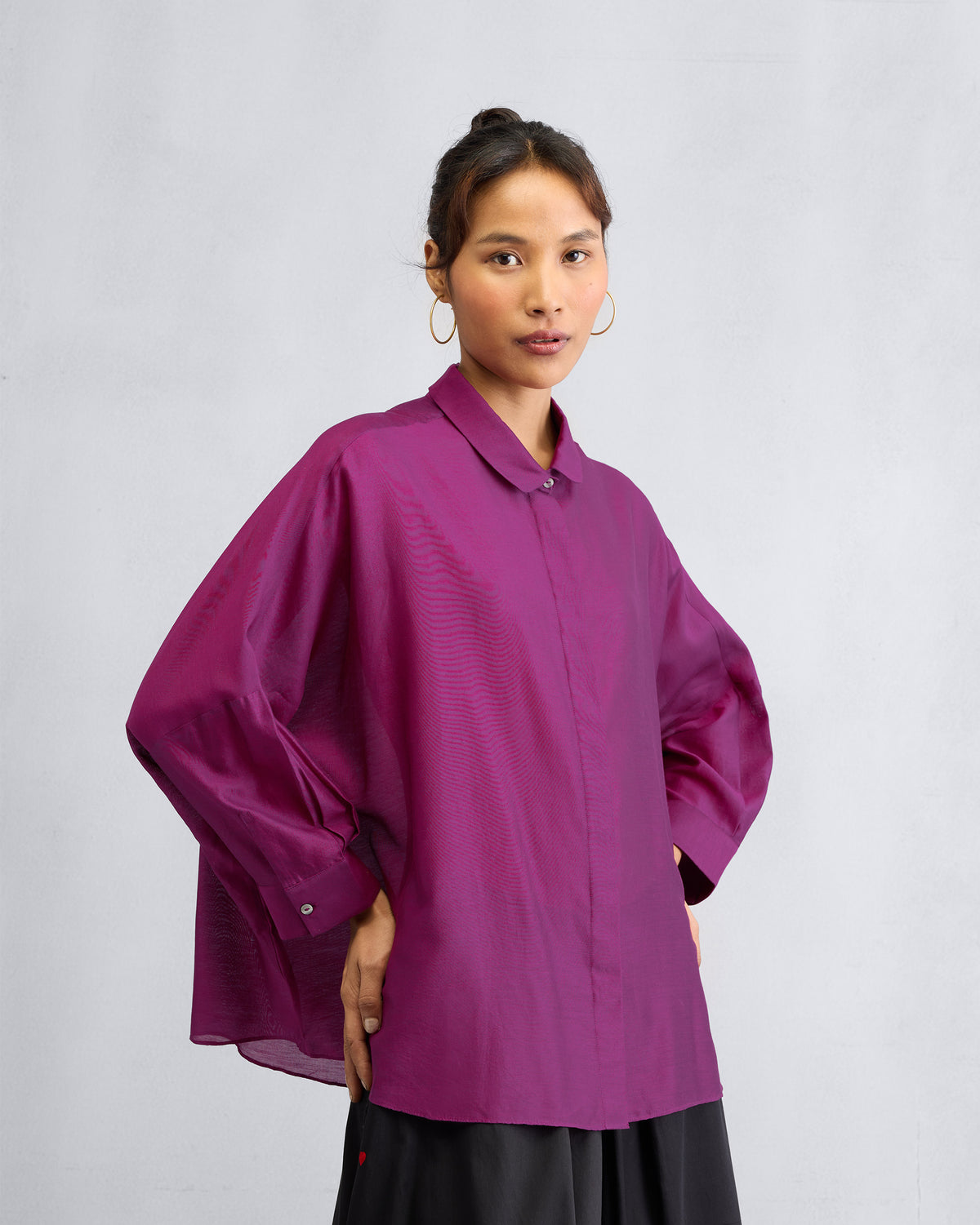 Person wearing a mulberry boxy shirt with voluminous sleeves gathered into cuffs.