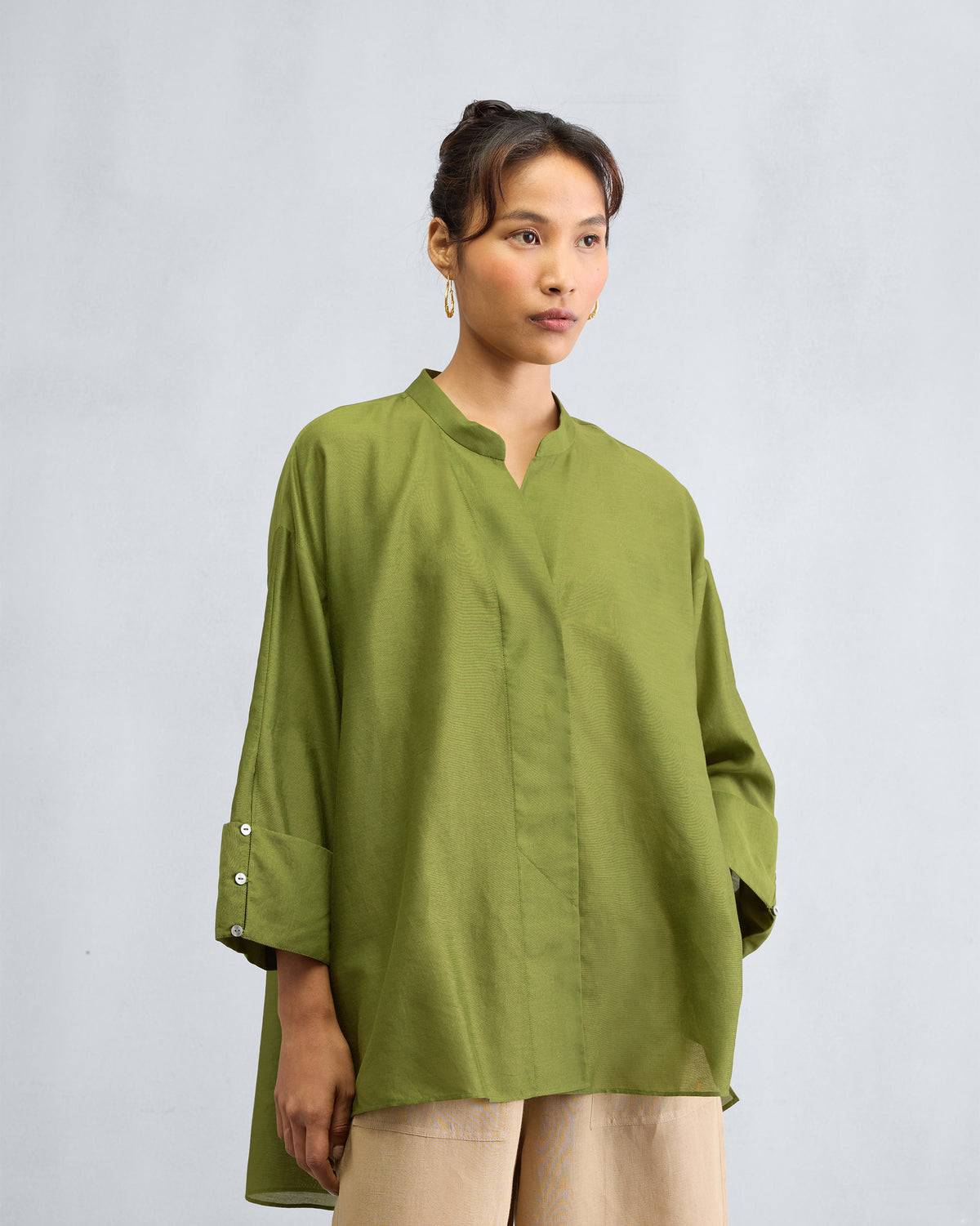 Person wearing an olive Cirrus shirt with a boxy fit and buttoned cuffs.