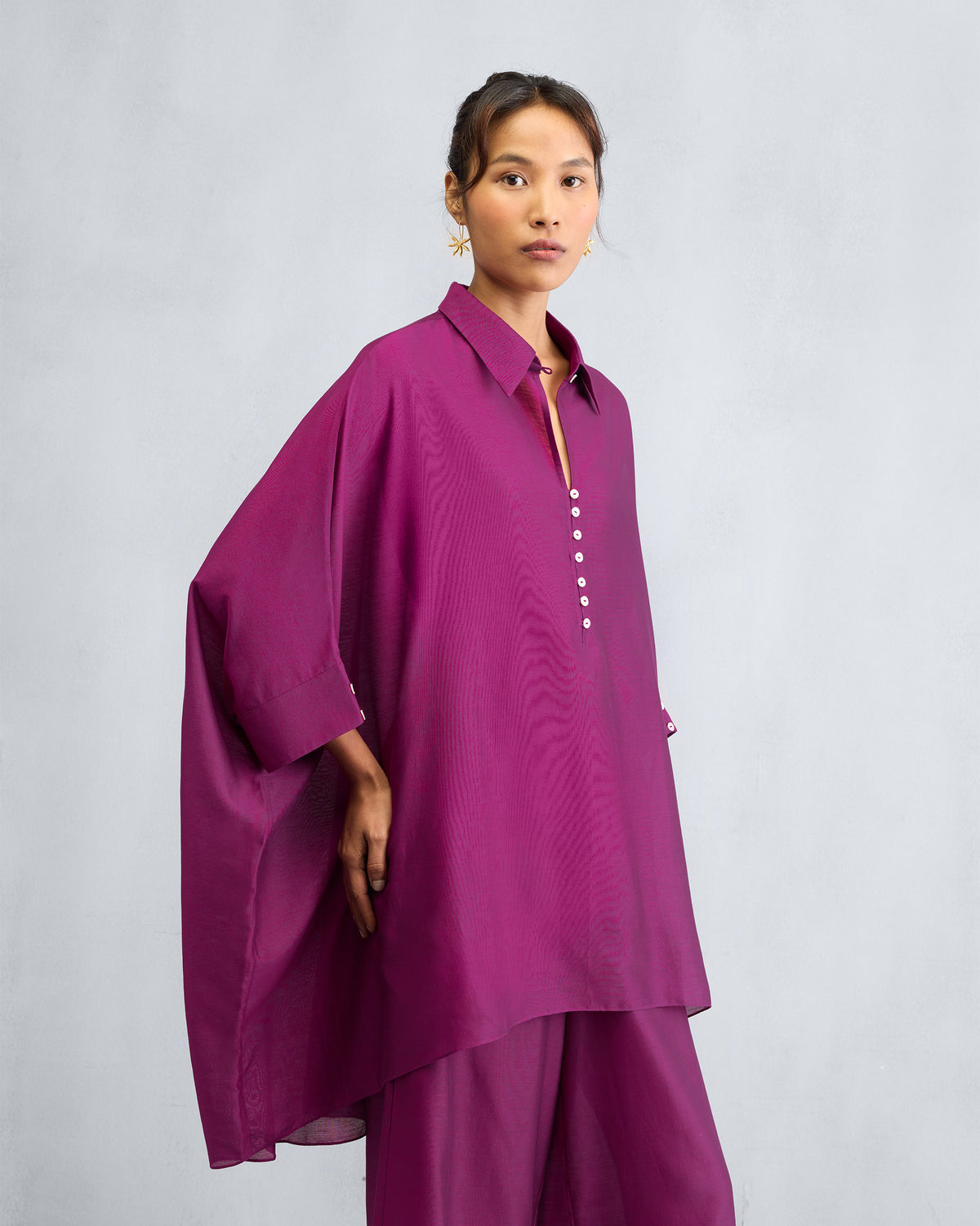 Person wearing a mulberry Hala tunic with wide draped sleeves.