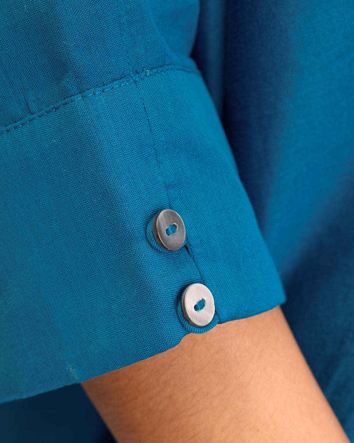 Close-up of the sapphire Hala tunic sleeve cuff with two white buttons.