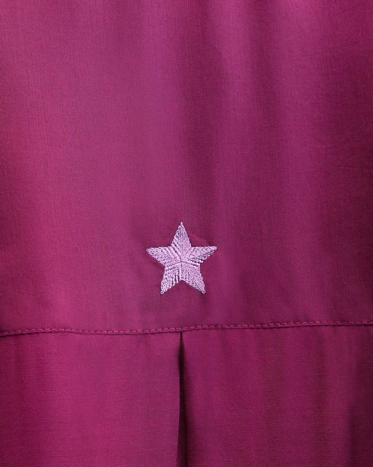 Close-up of a pale pink embroidered star on mulberry Lazy Sunday tunic fabric.