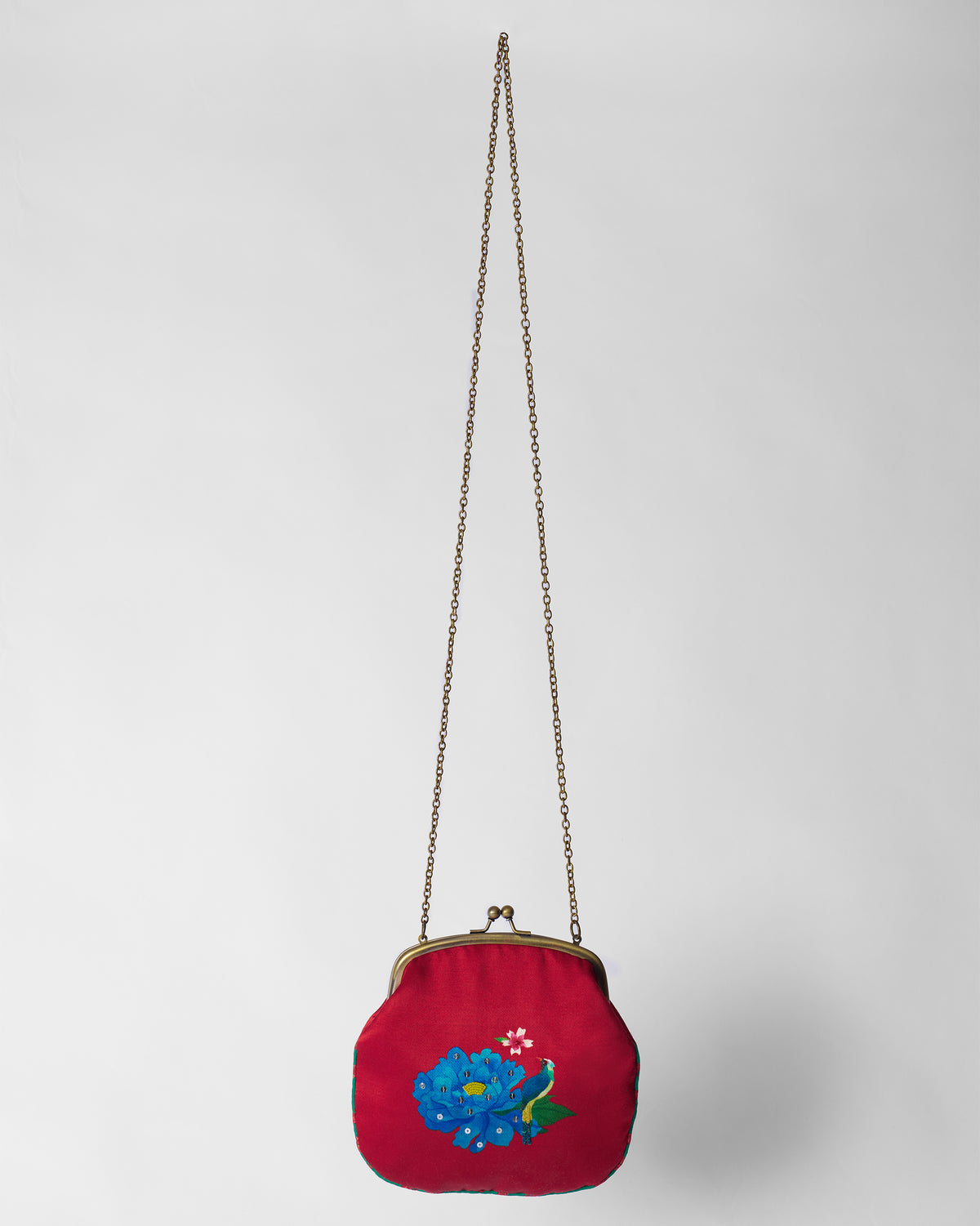 Red sling clutch showing a blue peony embroidery, kiss-lock, and long chain.
