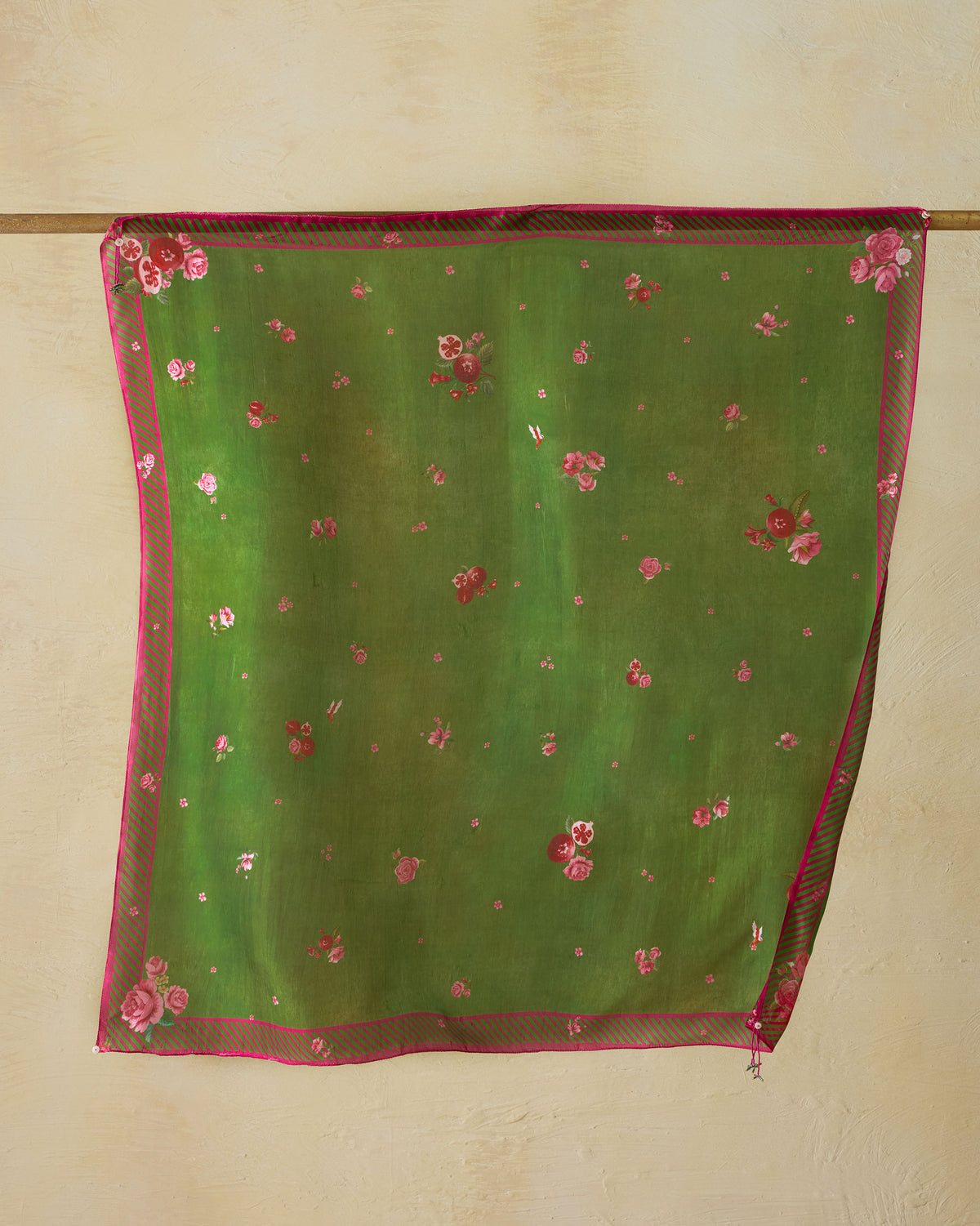 Bouquet Scarf in green with pink floral print and border, hung from a rod.