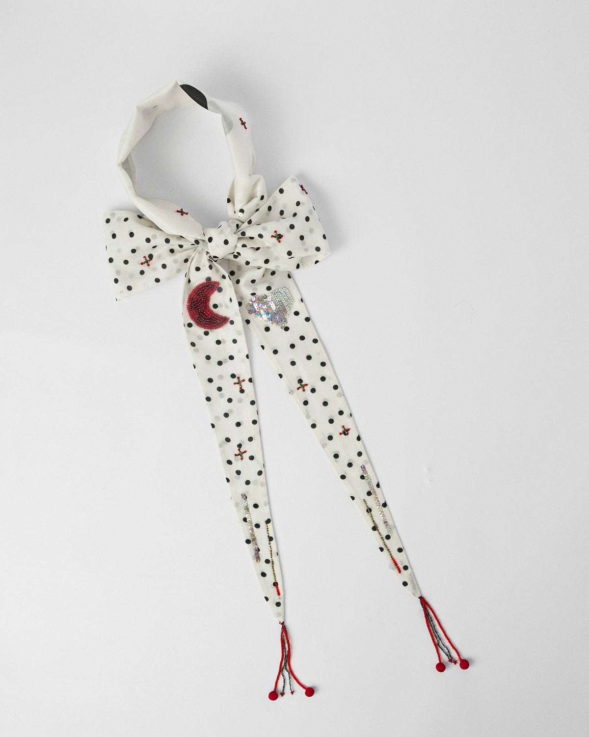 Ivory polka-dot scarf bow with a red crescent moon and sequin cloud motifs.