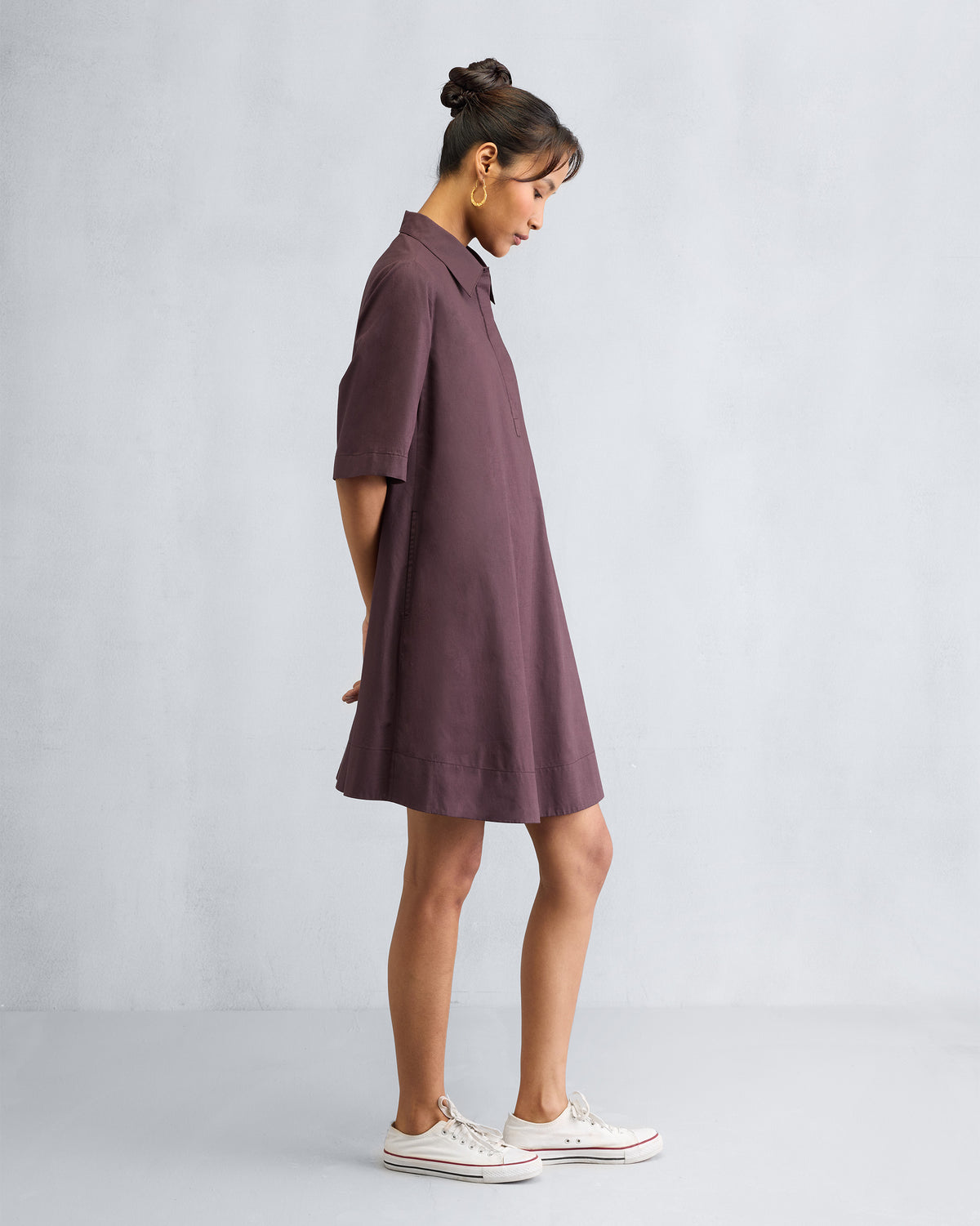Side view of a chocolate plum A-line short dress showing the flared hem.