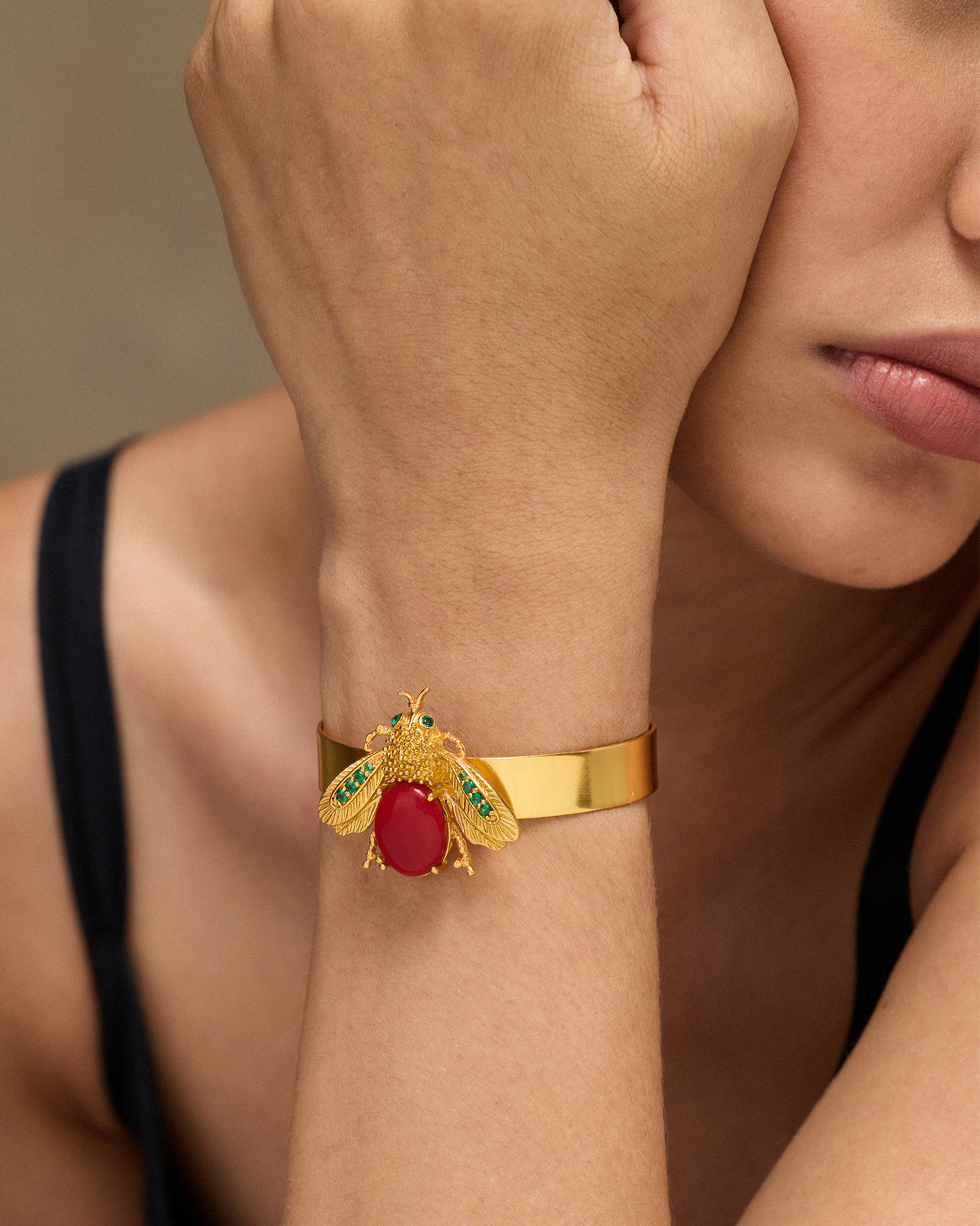 Gold Bug bracelet with a red stone insect motif worn on a wrist.
