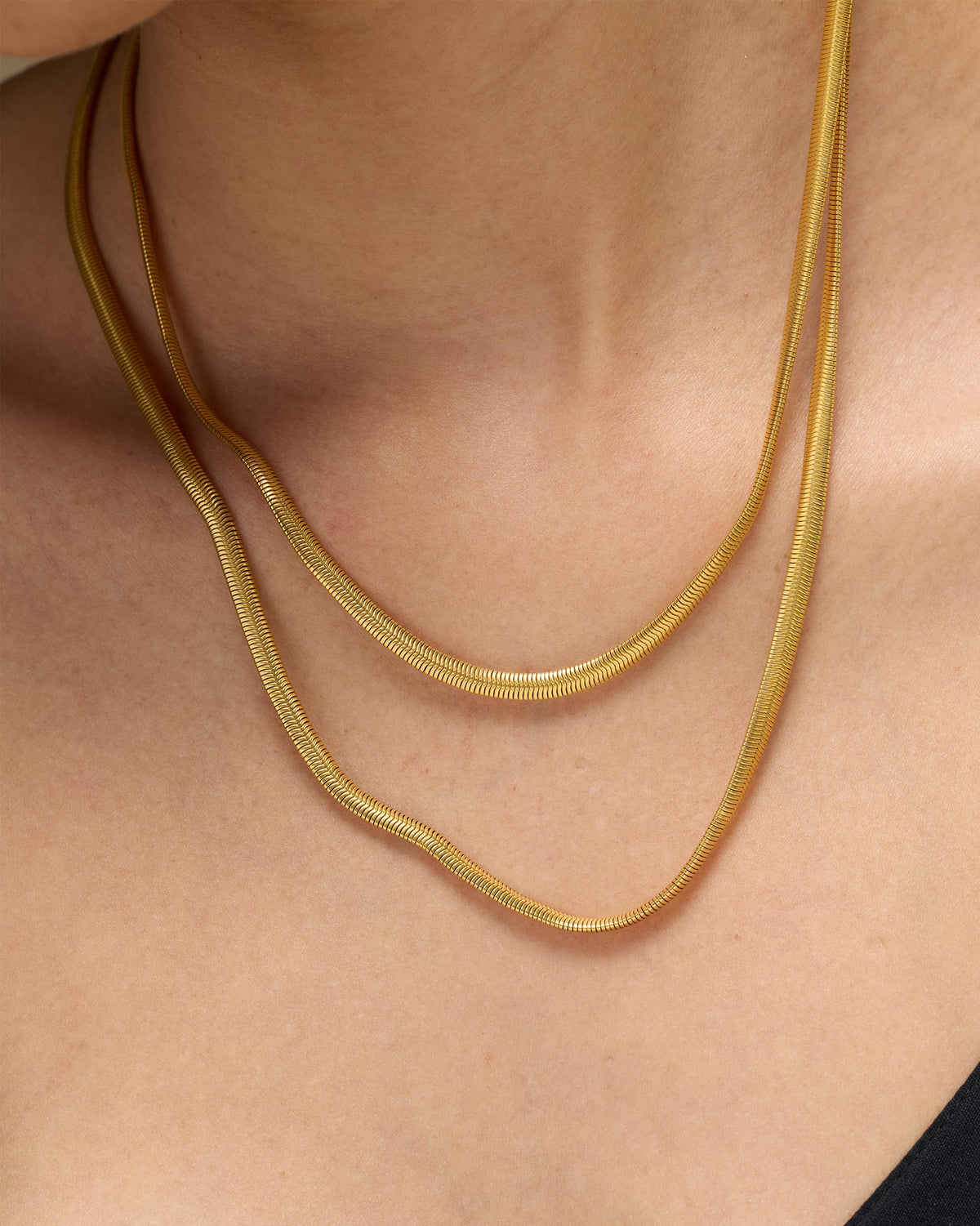 Close-up of a gold Layered Herringbone Chain worn in two strands.