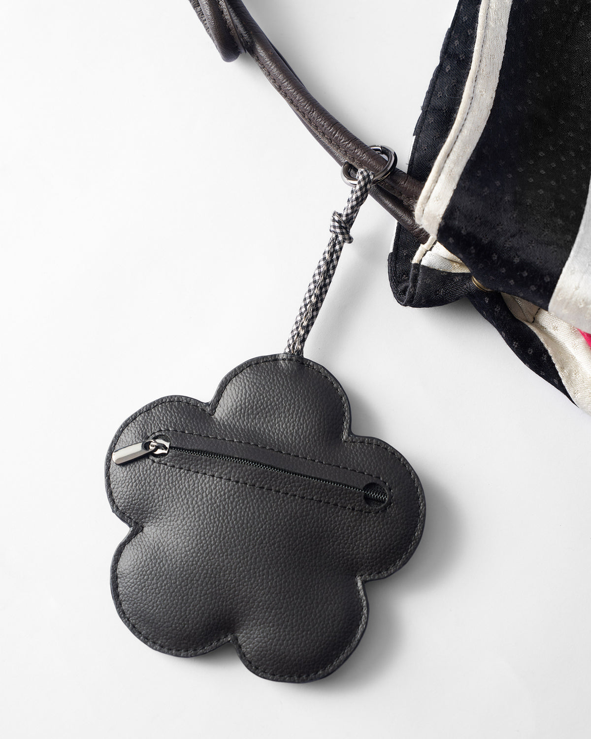 Black Flower Coin Pouch hanging from a bag strap, showing its zip along the lower edge.