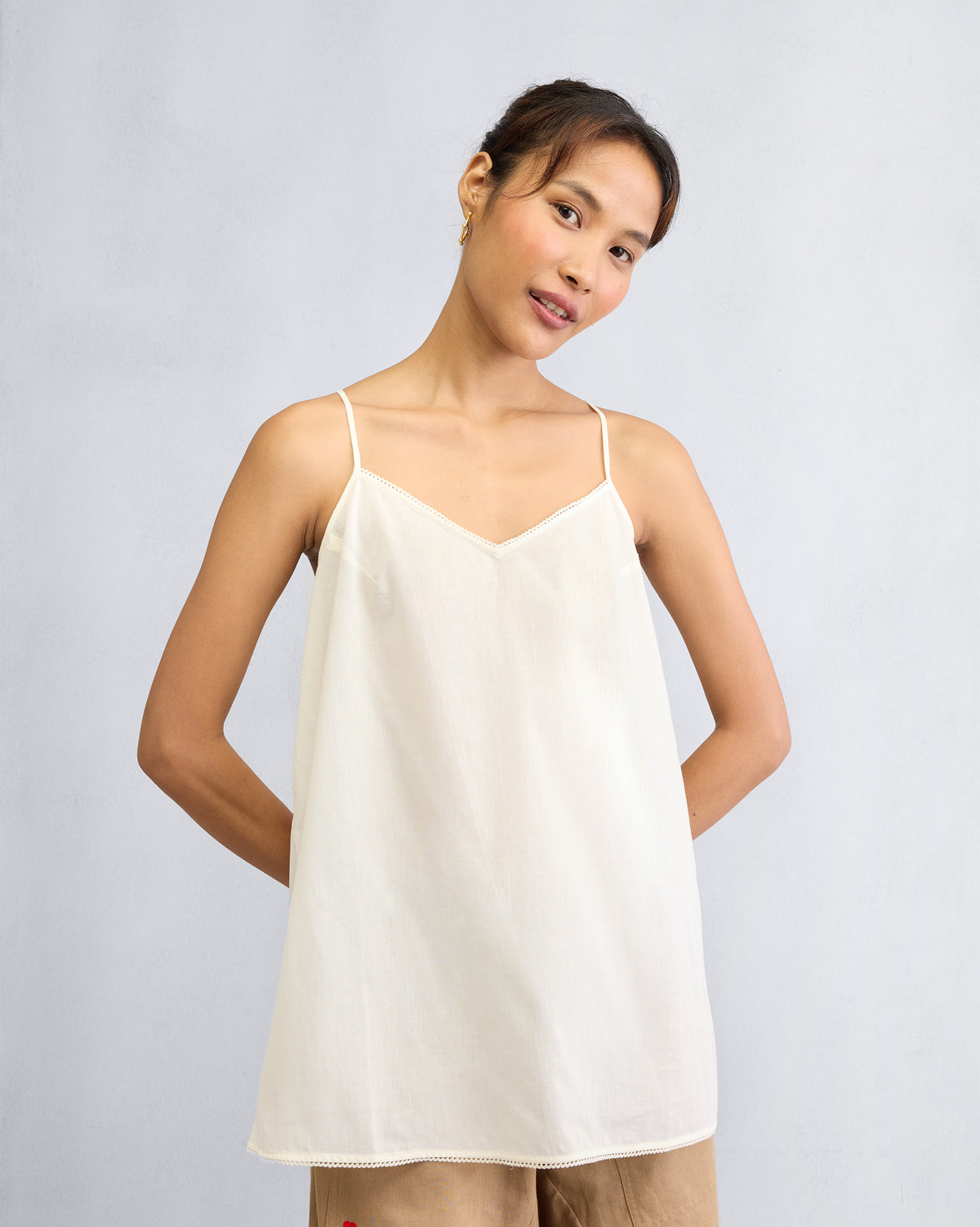 Person wearing an ivory Afra Camisole with thin spaghetti straps.