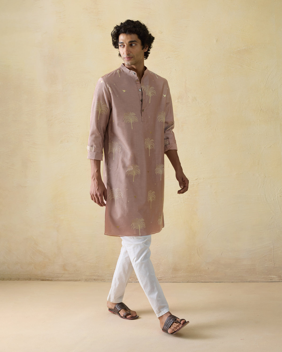 Person wearing a light pink Bageecha kurta with gold palm-tree print.