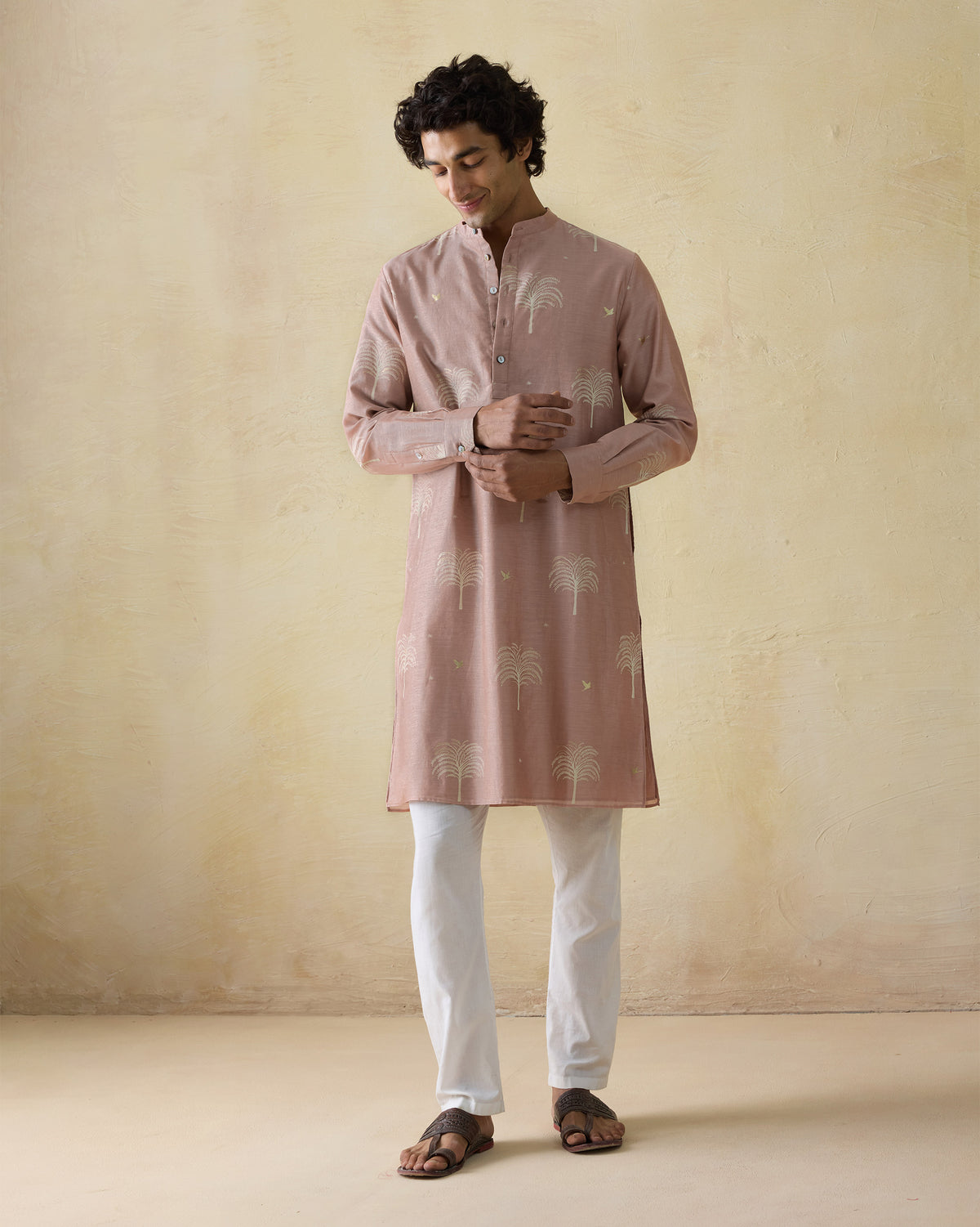 Person wearing a light pink Bageecha kurta with palm print, adjusting a cuff.